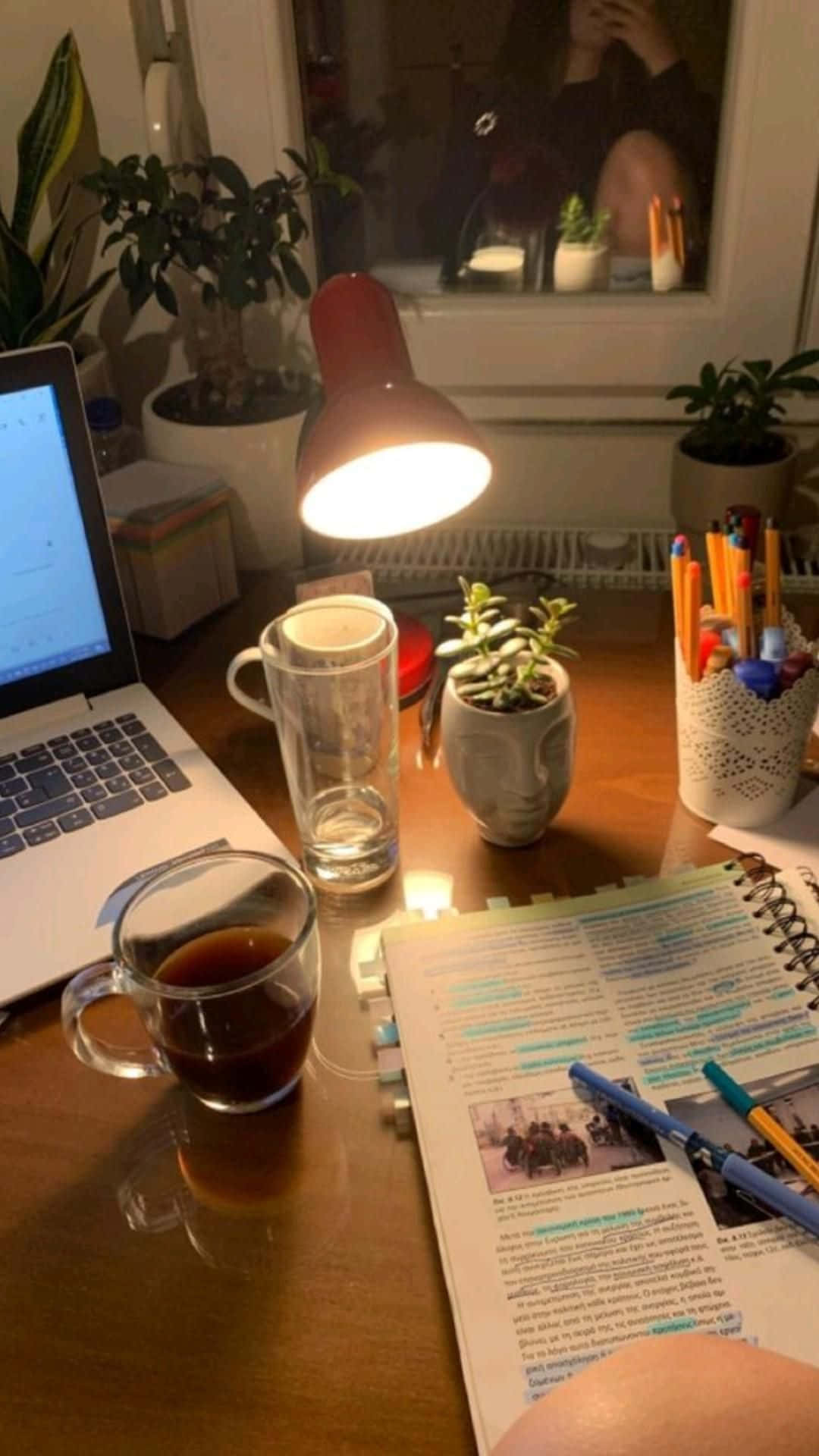  壁紙 — 一個舒適的夜間書桌，由溫暖的燈光照亮，配有咖啡、筆記本和植物。