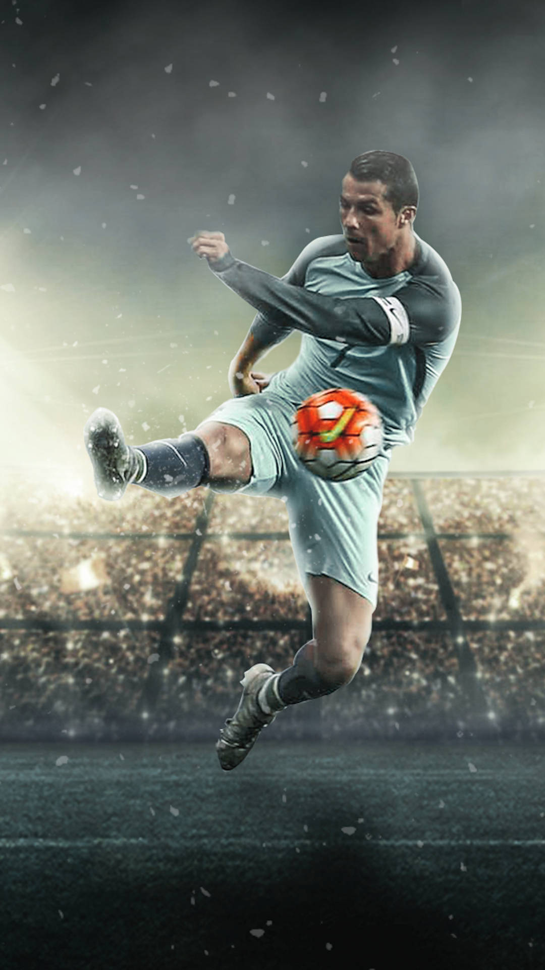 CR7 踢球瞬間 克里斯蒂亞諾·羅納度 iPhone 壁紙 — 一名足球員在球場中，在戲劇性燈光下，於空中踢球，同時有雪飄落。