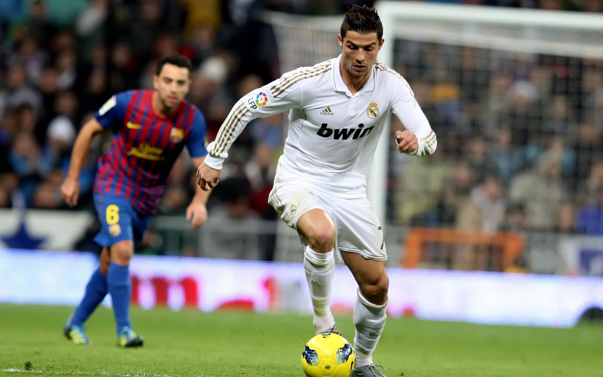 CR7 足球運動員 壁紙 — 基斯坦奴·朗拿度在綠色球場上盤扭一個黃色足球，一名身穿藍紅色的巴塞隆拿球員正在追趕他。