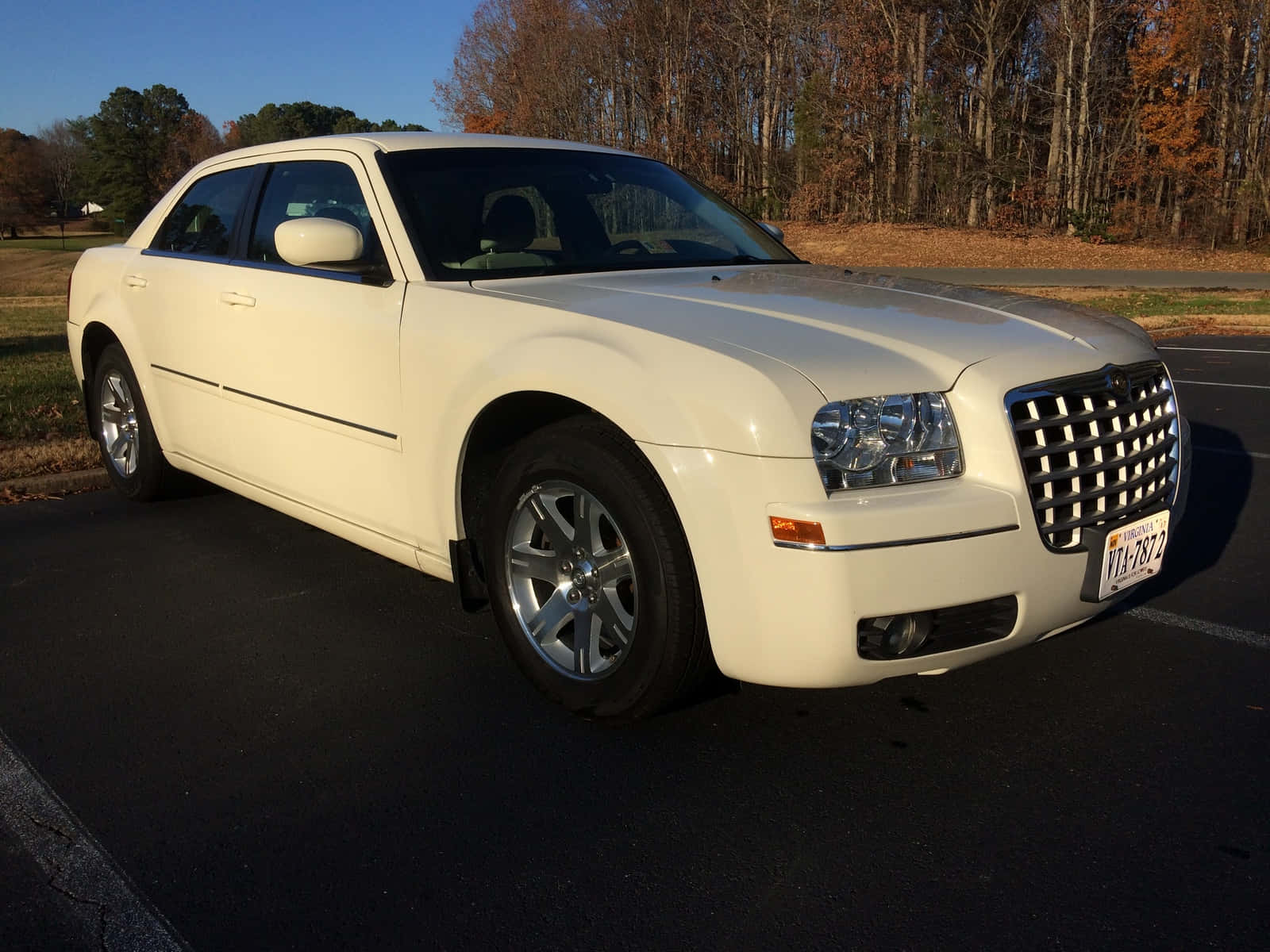 Chrysler 300 桌布 壁紙 — 一輛奶油色的 Chrysler 300 轎車在午後的陽光下閃閃發光，停在瀝青路上，背景是秋天的樹木。
