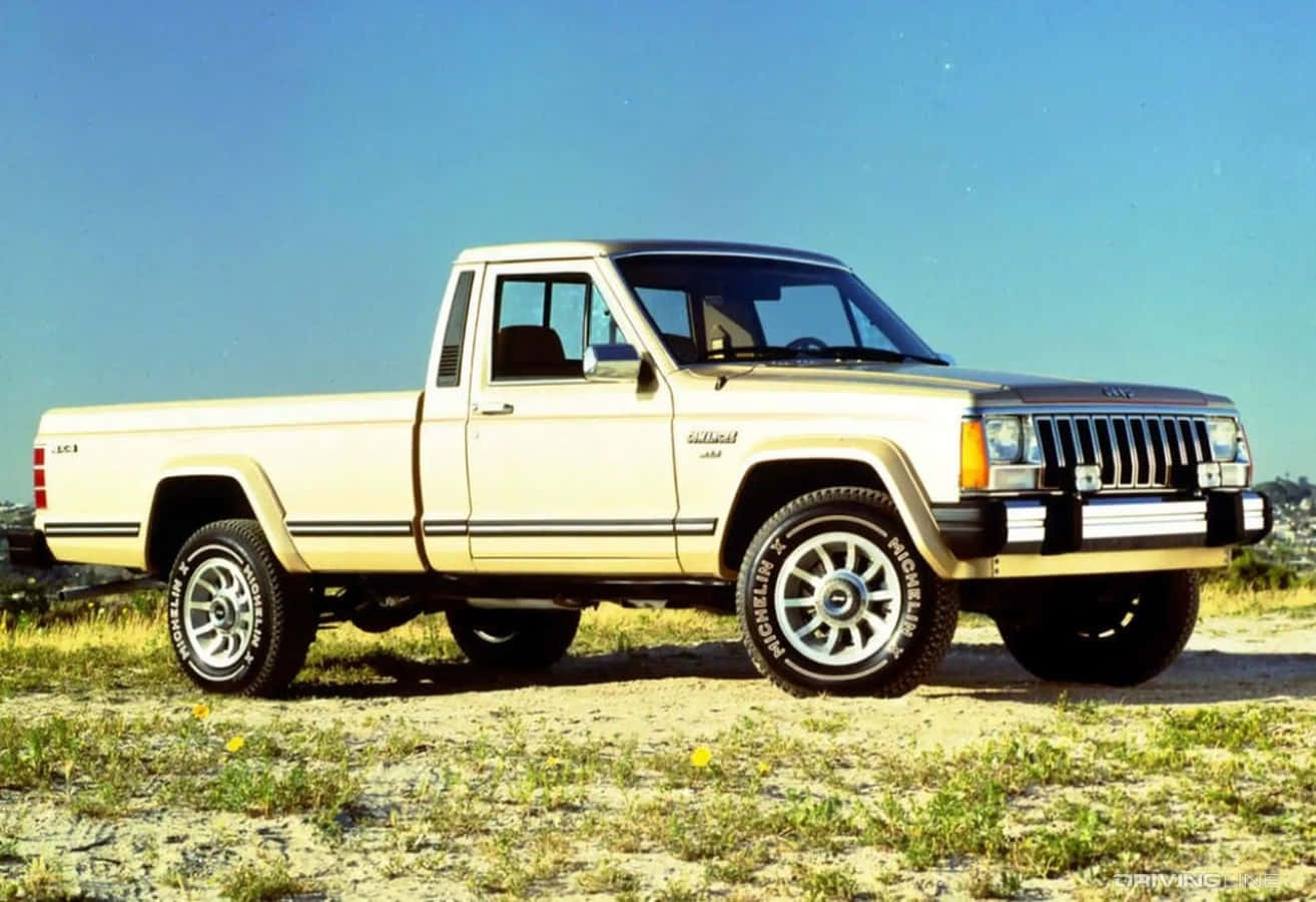 Jeep Comanche 桌布 壁紙 — 一輛奶油色的Jeep Cherokee皮卡車停在乾草地上，天空湛藍清澈。