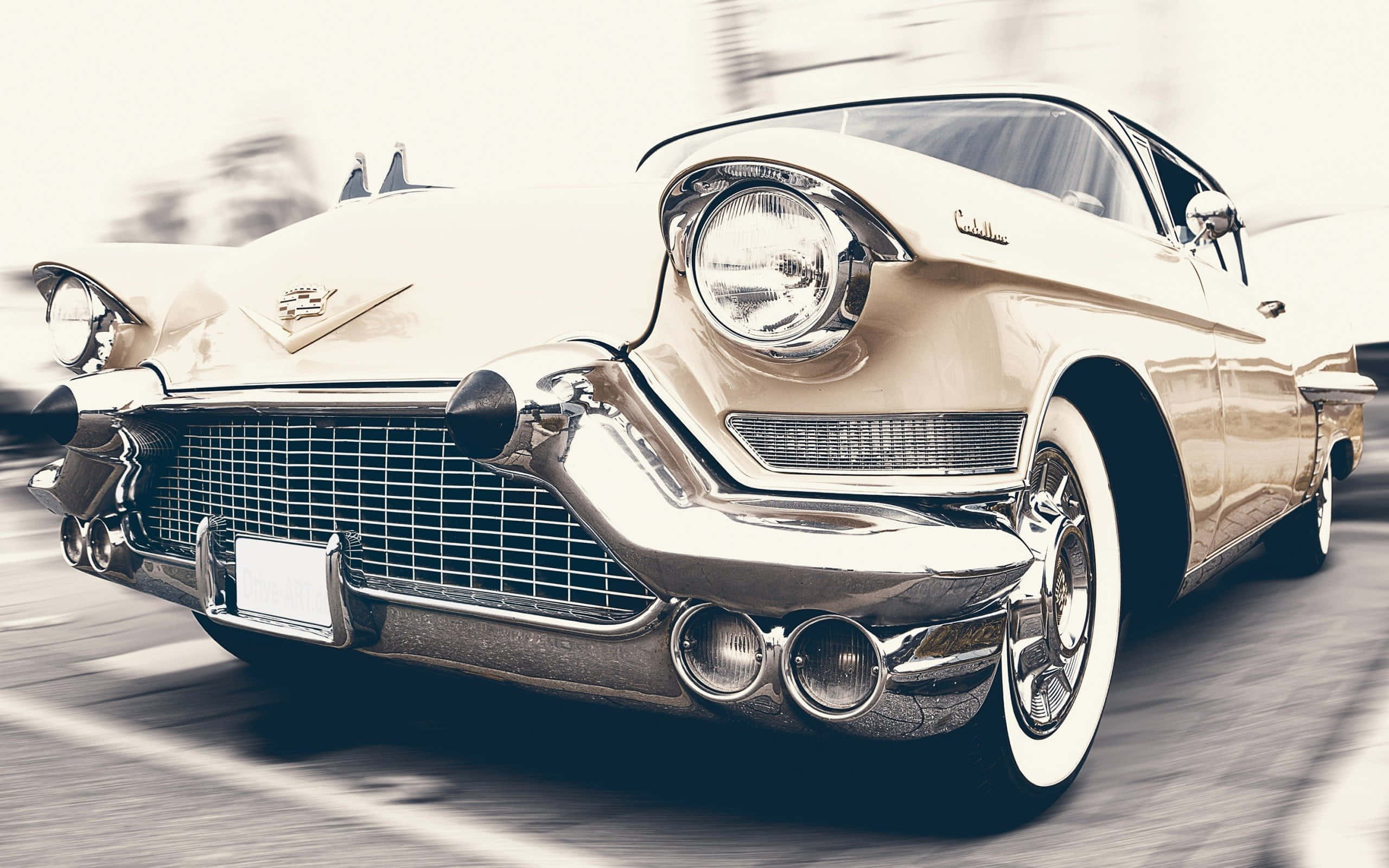 Cadillac Eldorado 桌布 壁紙 — 一輛奶油色的1950年代凱迪拉克向前飛馳，帶有鍍鉻裝飾和模糊的運動線條，強調其復古力量。