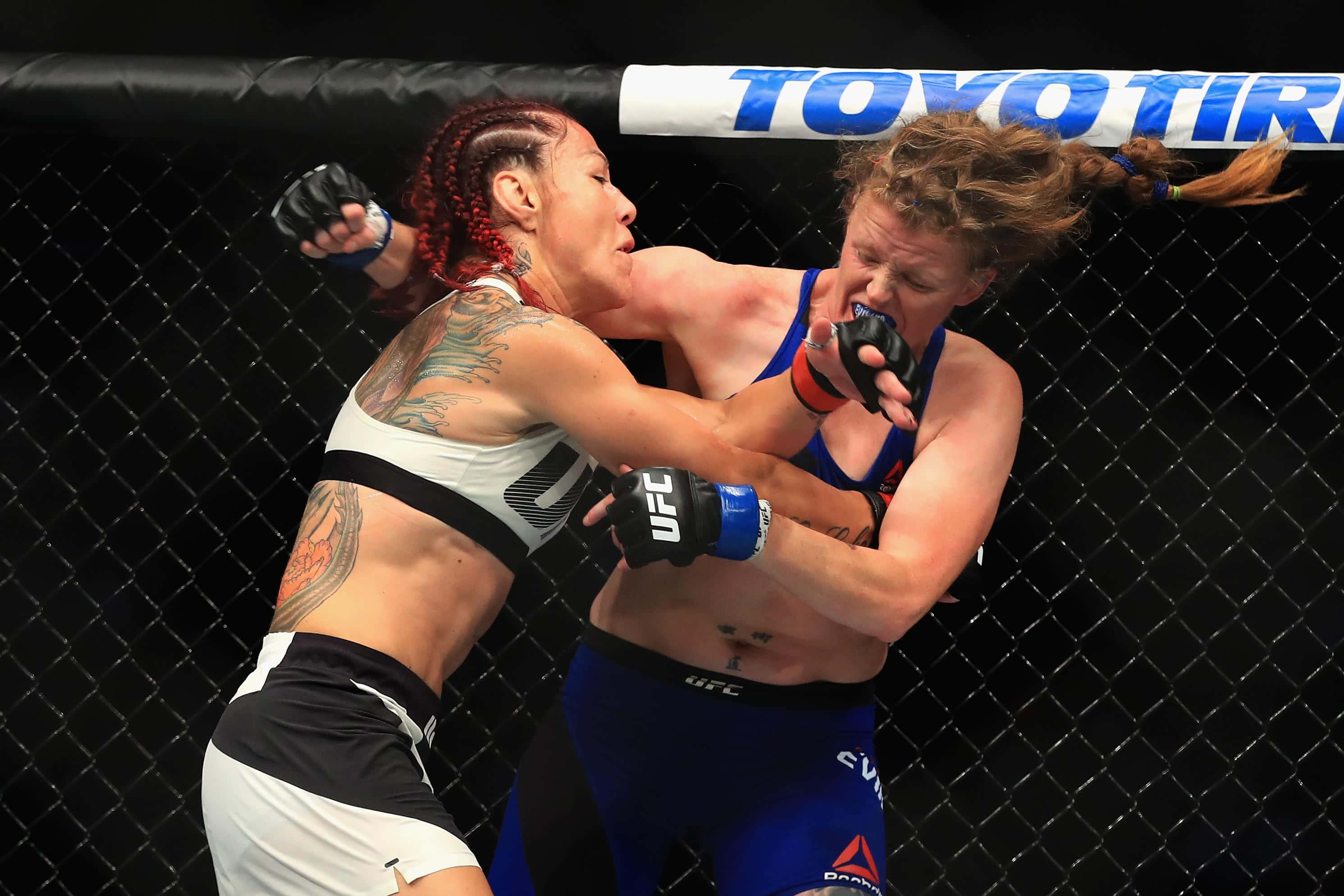 Cris Cyborg對戰Tonya Evinger UFC 214精彩瞬間 壁紙 — 兩名女性MMA拳手在激烈的鐵籠賽中交鋒，紋身和手套飛舞。