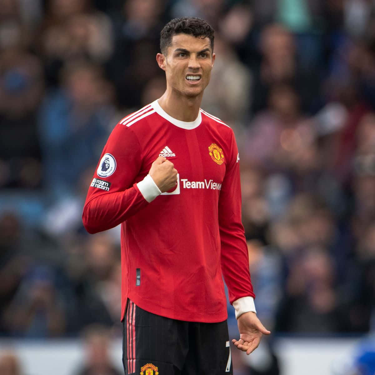Cristiano Ronaldo 桌布 壁紙 — Cristiano Ronaldo 身穿紅色曼聯球衣，在比賽中握緊拳頭，背景是模糊的球場人群。