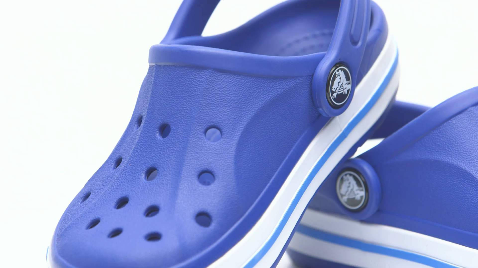 兒童藍色 Crocs 沙灘鞋 壁紙 — 鮮豔藍色Crocs木屐的特寫，帶有白色和淺藍色條紋，背景為純白色。