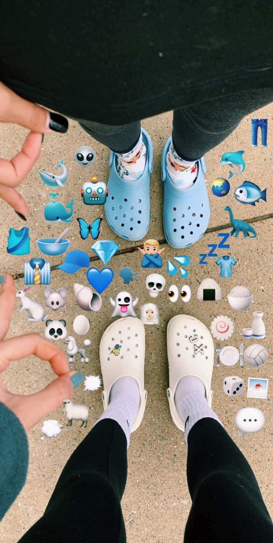 一雙舒適的Crocs鞋 壁紙 — 兩個穿著Crocs的人站在行人路上，周圍散落著藍色表情符號貼紙。