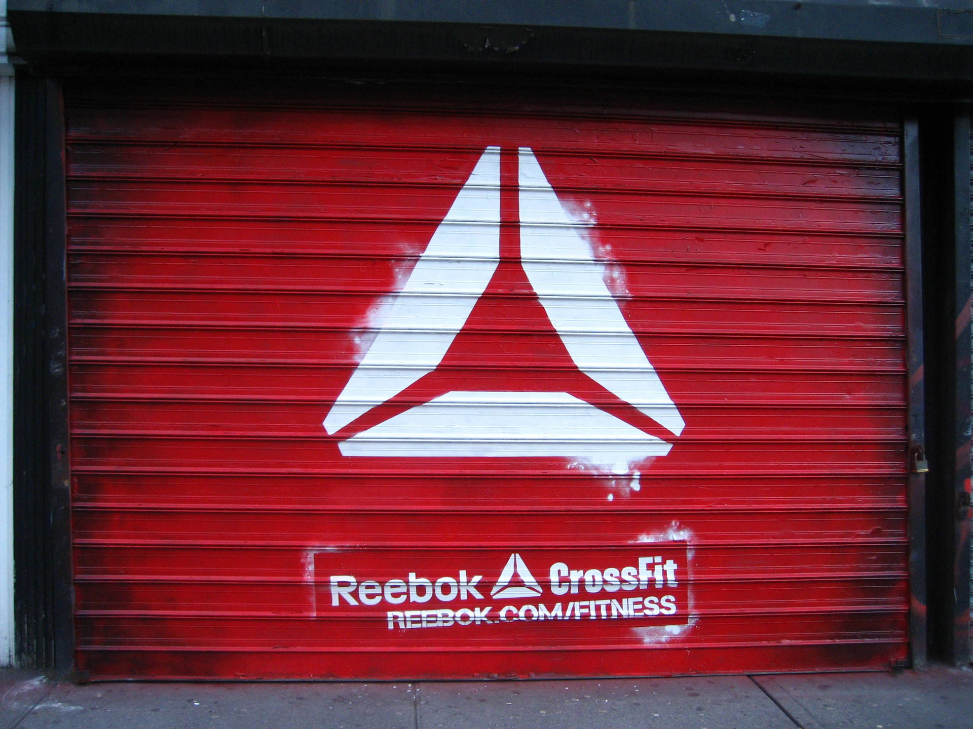紅色金屬快門門，帶有白色Reebok CrossFit標誌和網站文字。