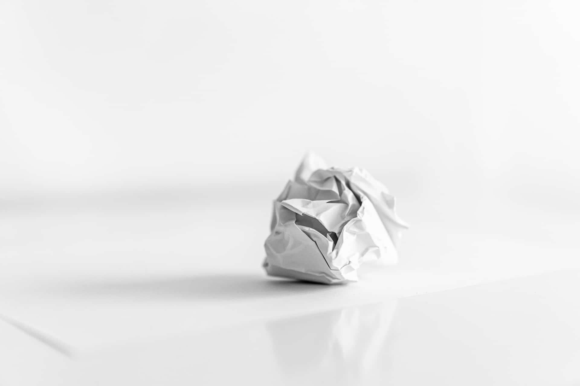 皺巴巴的白色紙球在反射的白色表面上。