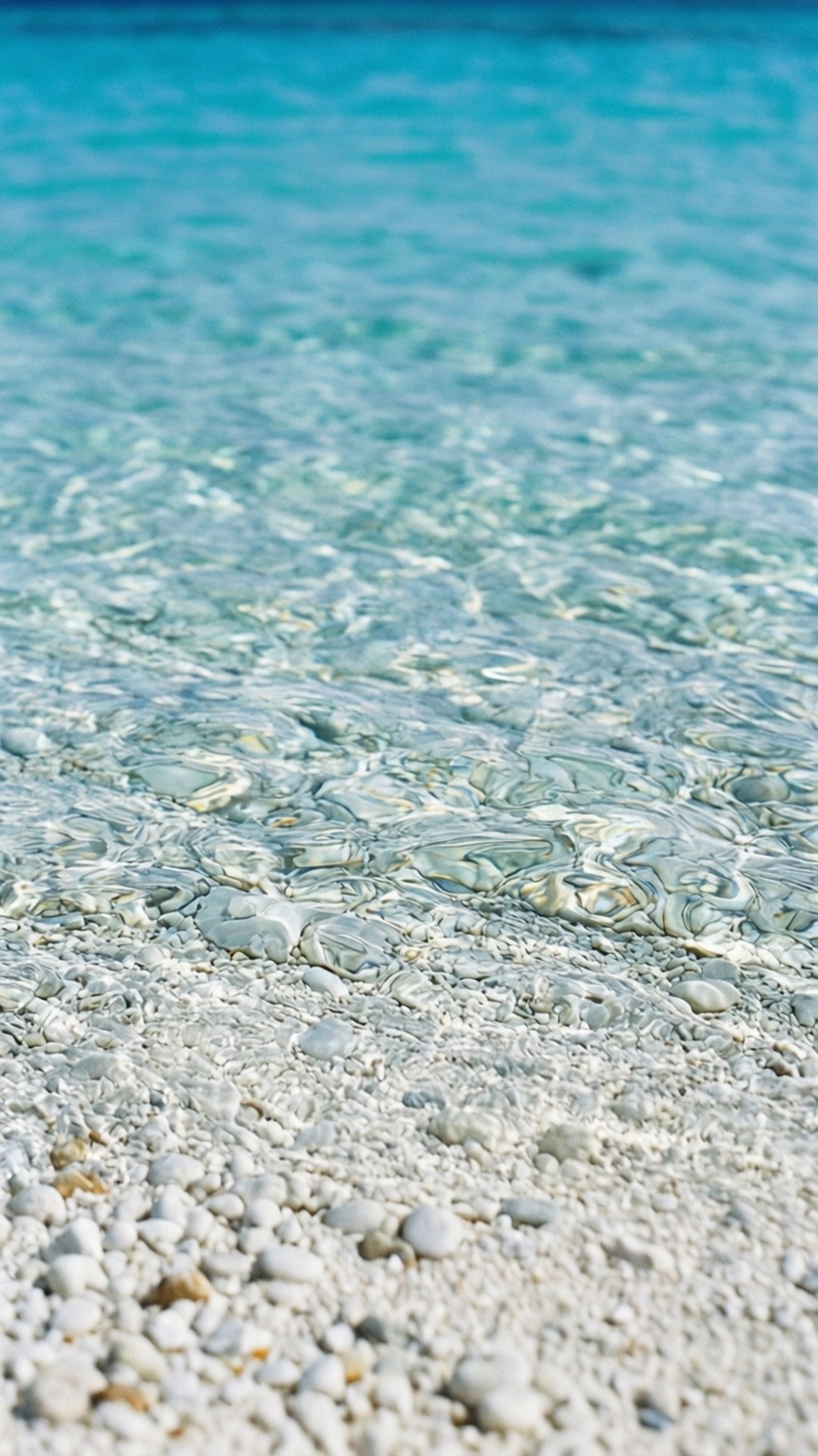 淺碧綠海水在陽光明媚的海灘上流過白色鵝卵石