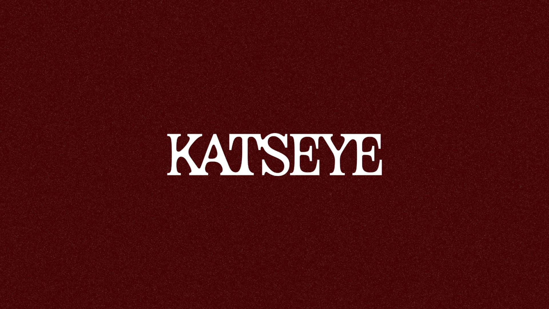  壁紙 — 粗體白色襯線文字 katseye 居中於帶紋理的深酒紅色背景上。