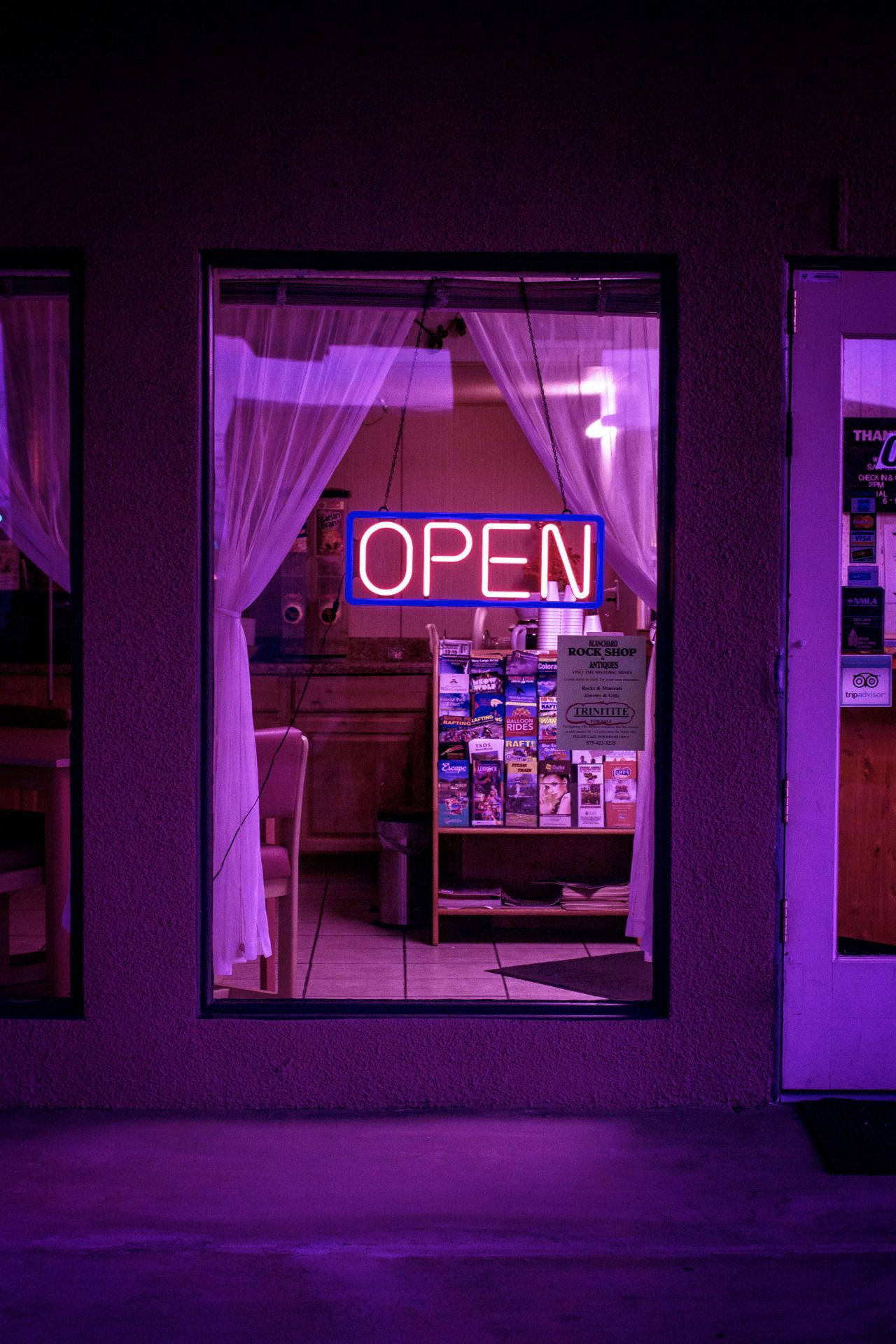 夜晚黑暗商店櫥窗中的紫色霓虹燈「open」標誌。
