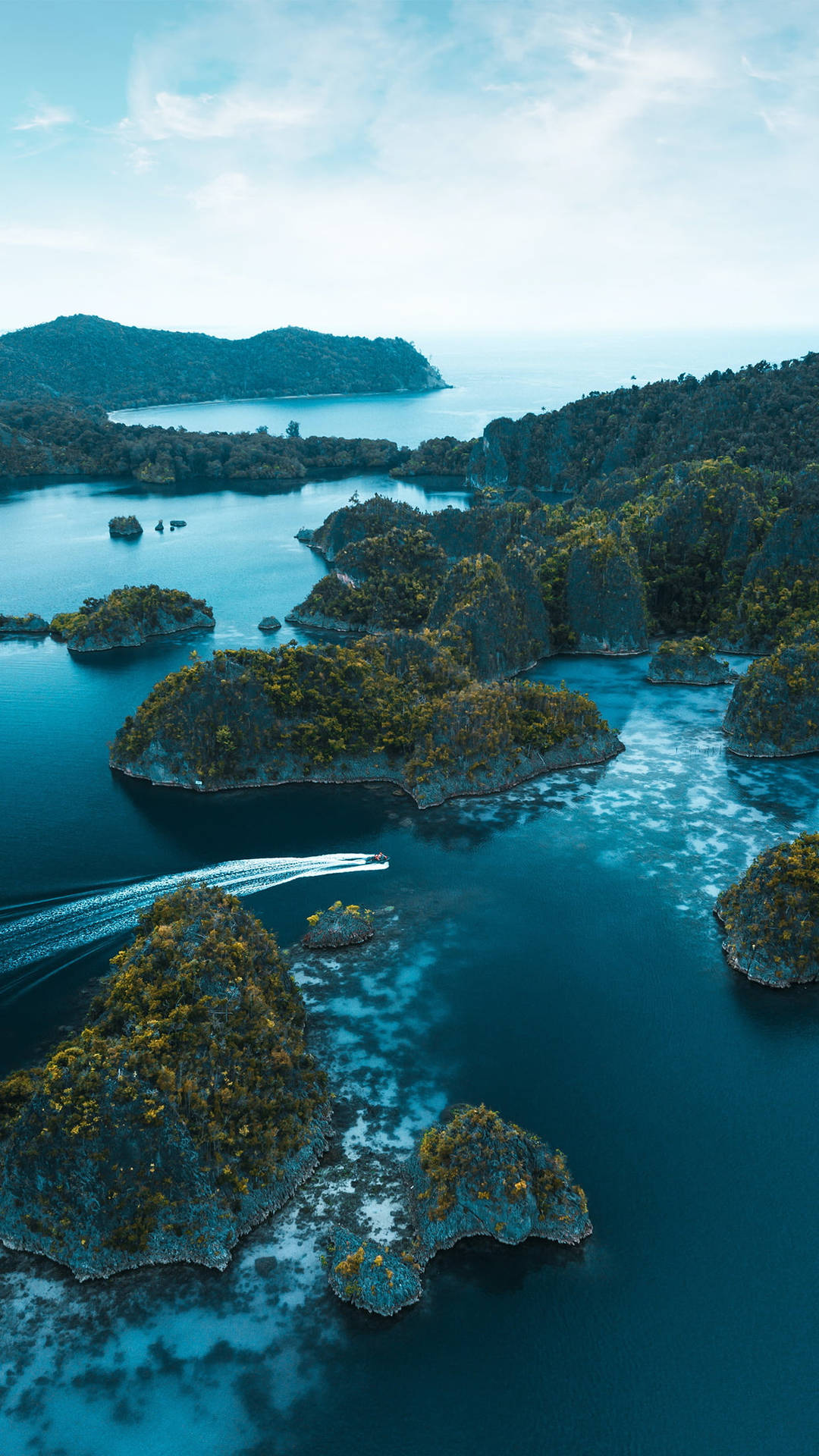 快艇在翠綠島嶼之間的碧綠海面上滑行。