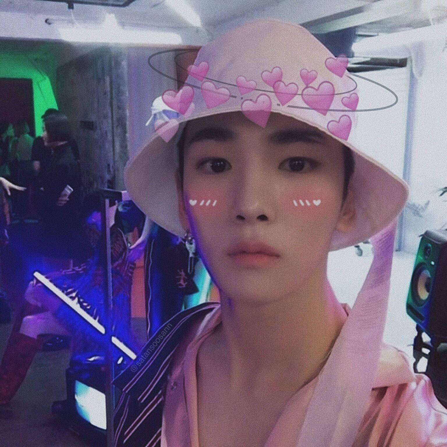 Cute Shinee Key 壁紙 — 一位年輕人戴著粉紅色漁夫帽，帽上飾有心形軌道圖案，眼睛下方有腮紅痕跡，身處霓虹燈照亮的房間。