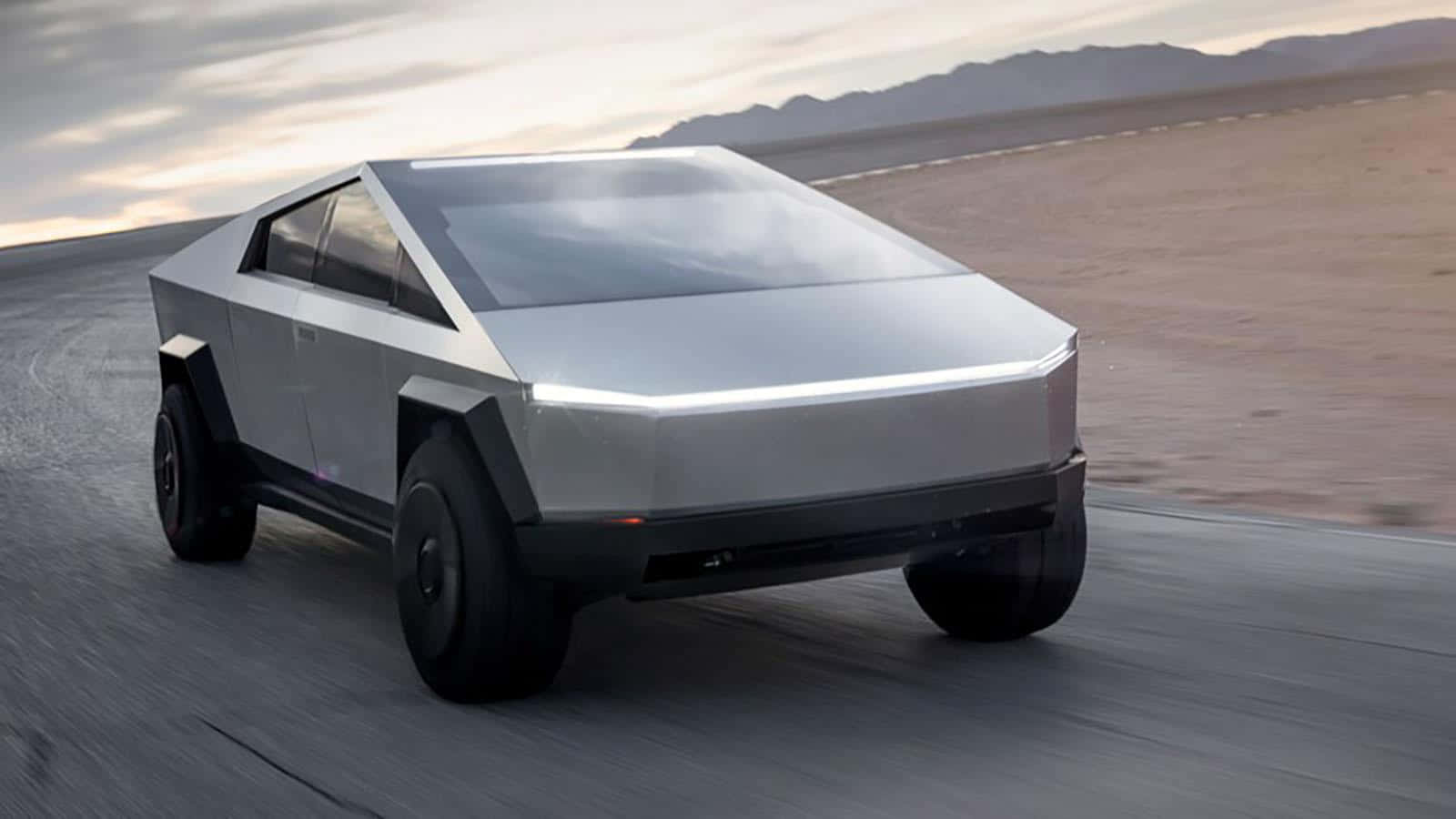 特斯拉Cybertruck——未來電動車設計的巔峰之作 壁紙 — 一輛銀色 Tesla Cybertruck 在沙漠公路上疾馳，背景是山脈，天空呈現柔和的暮色。