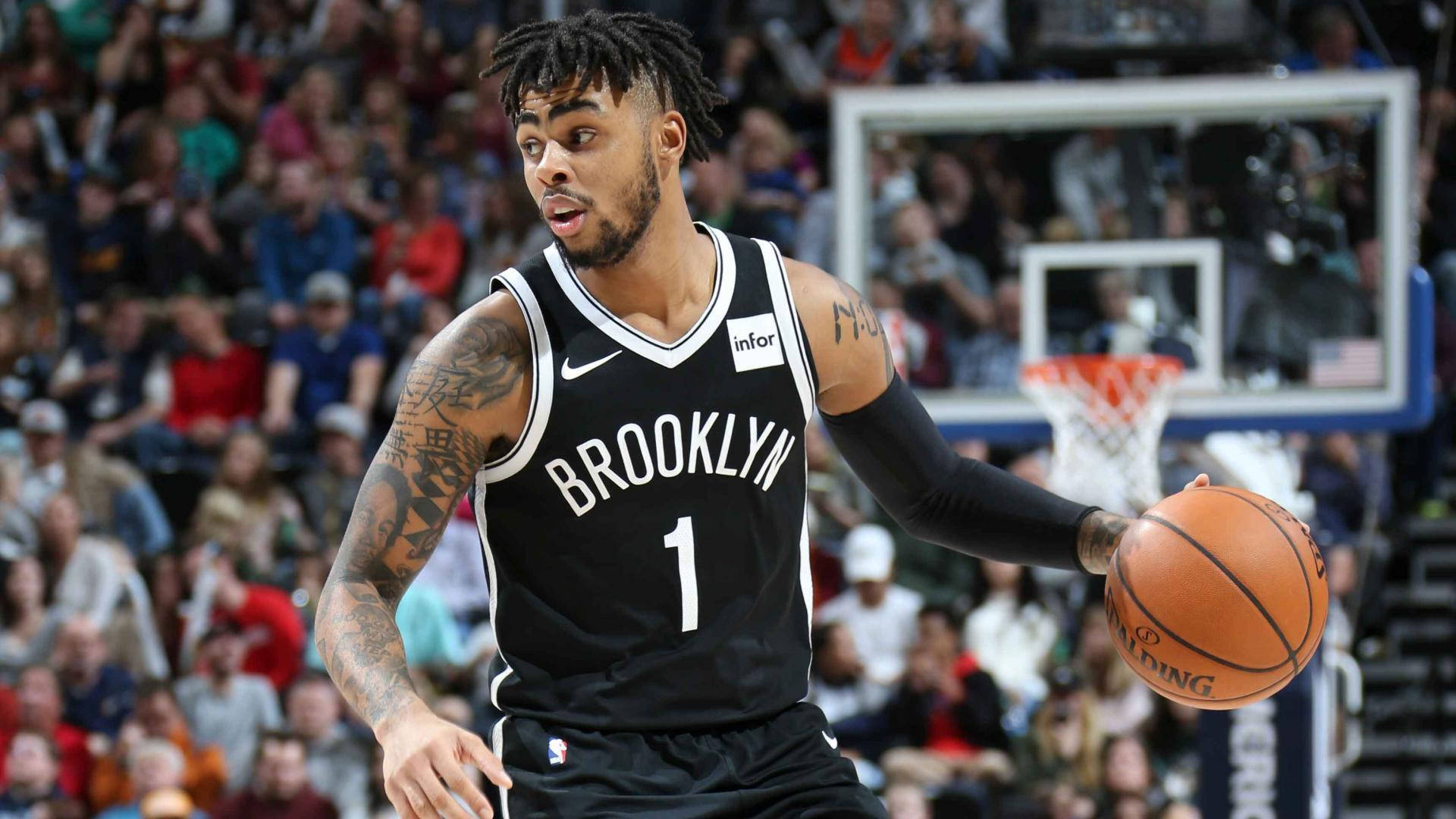 D'Angelo Russell 最佳 NBA 球員 壁紙 — 一名身穿黑色球衣的布魯克林籃網籃球運動員在激烈的比賽中運球，背景是座無虛席的人群。