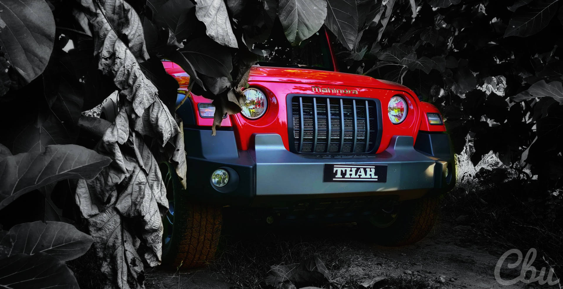 紅色Mahindra Thar SUV部分被叢林環境中的大暗葉遮擋。