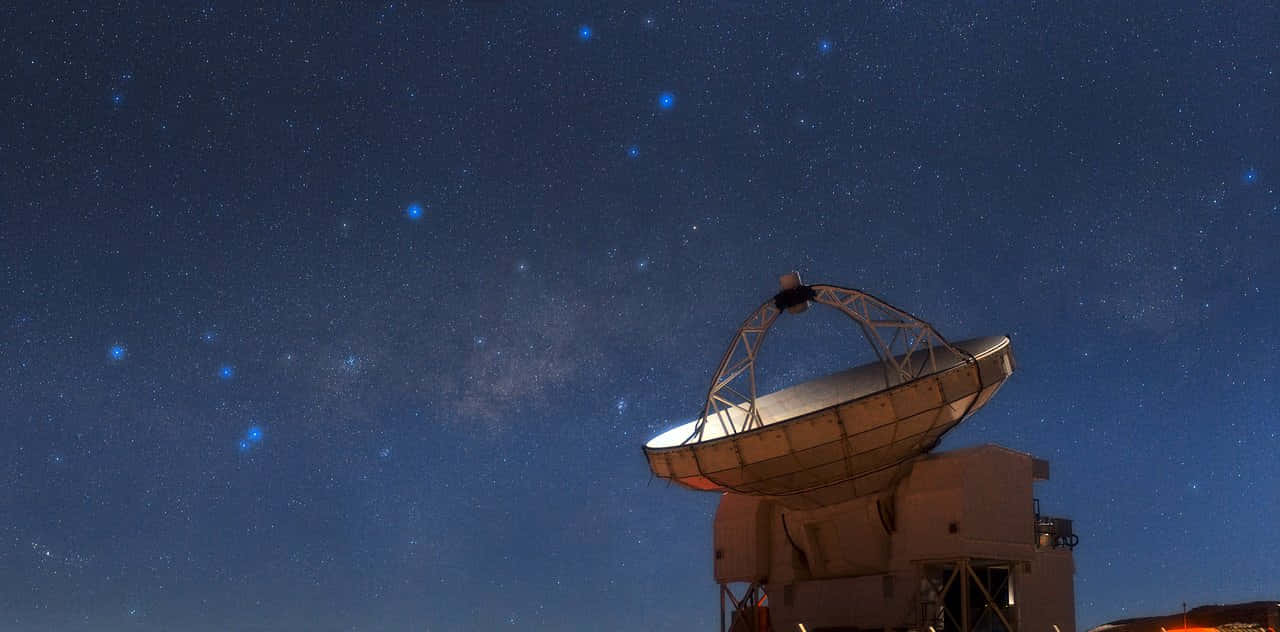  壁紙 — 一個大型無線電望遠鏡矗立在繁星點點的夜空下，銀河系在上方微微發光。