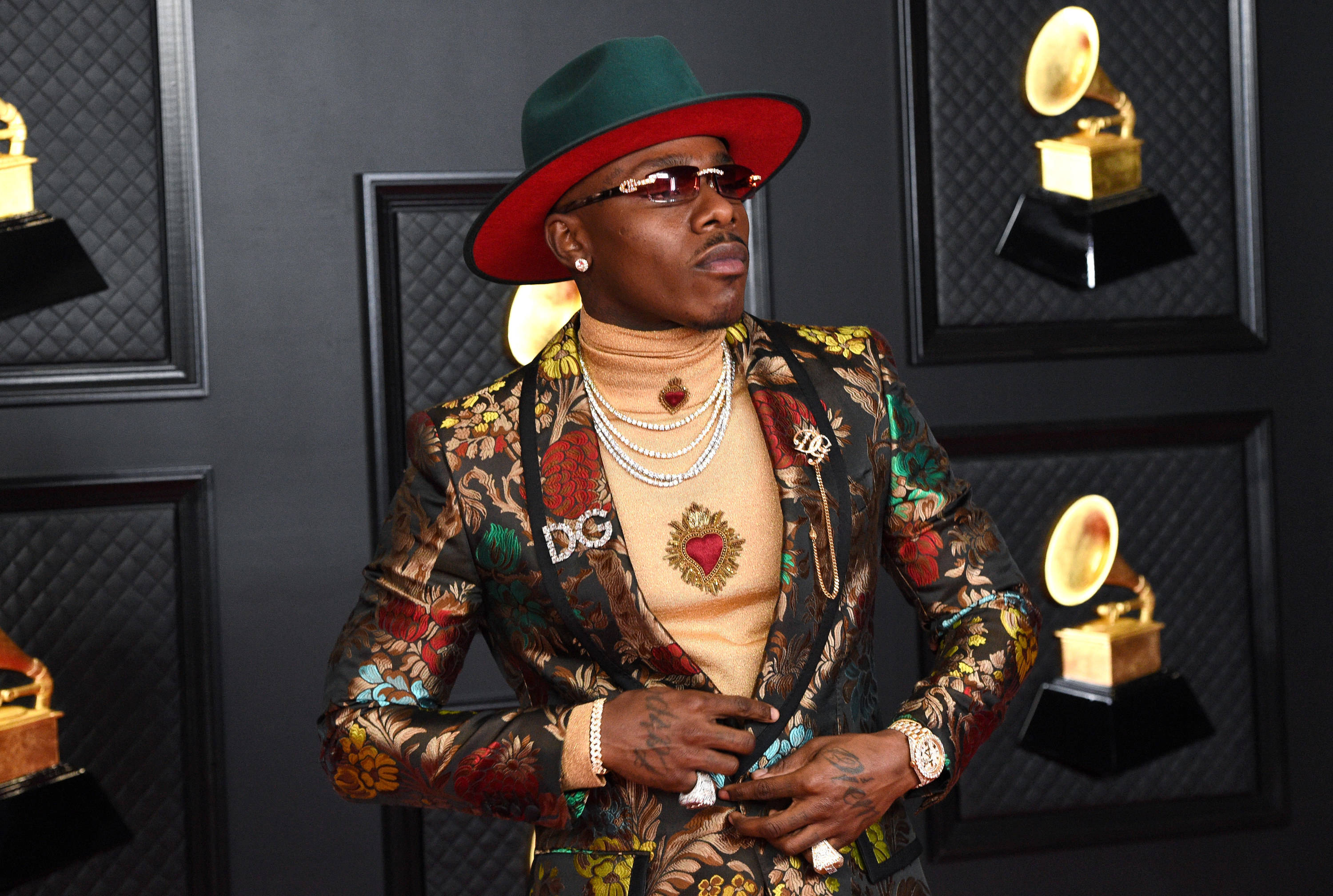 Dababy 在第63屆格萊美獎 壁紙 — 一位時尚男士戴著紅色內襯的綠色帽子和花卉圖案西裝外套，在葛萊美獎背景下自信地擺姿勢。