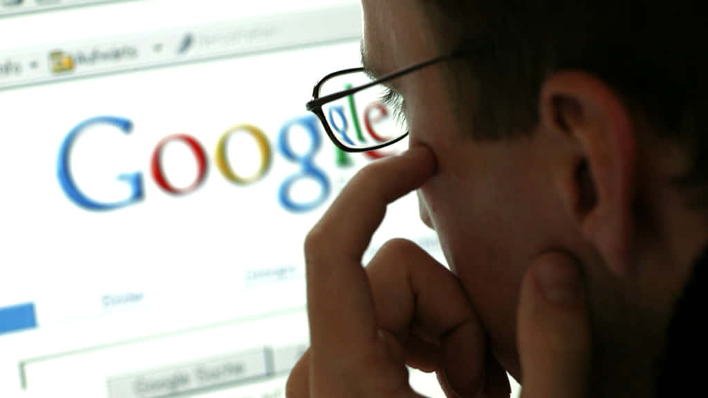 戴眼鏡的人看著電腦上的Google搜尋頁面思考。