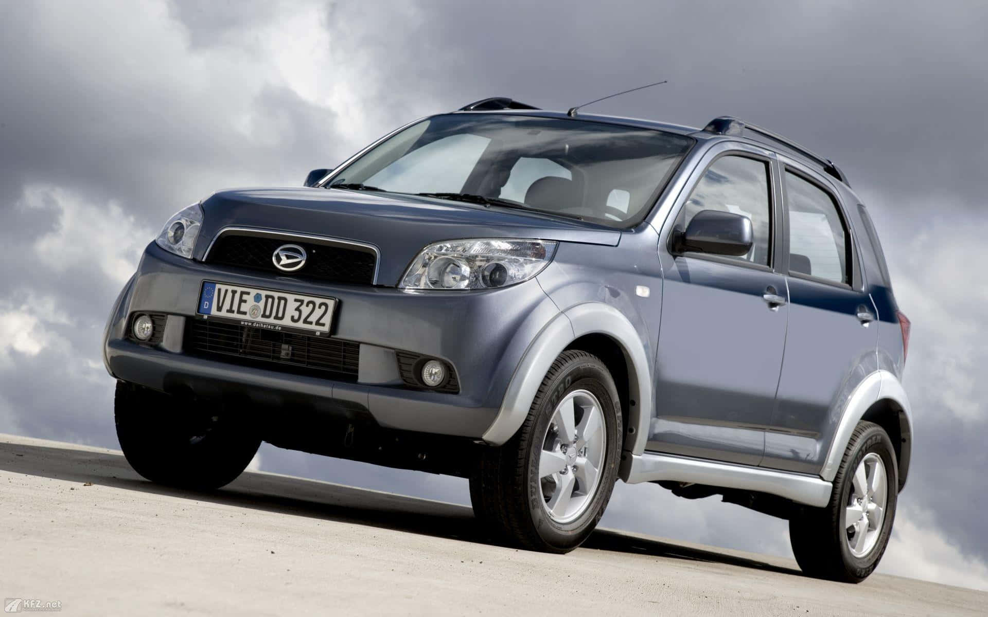 路上型格又時尚嘅Daihatsu 壁紙 — 一輛時尚的銀色SUV在戲劇性的多雲天空下停放在混凝土表面上。
