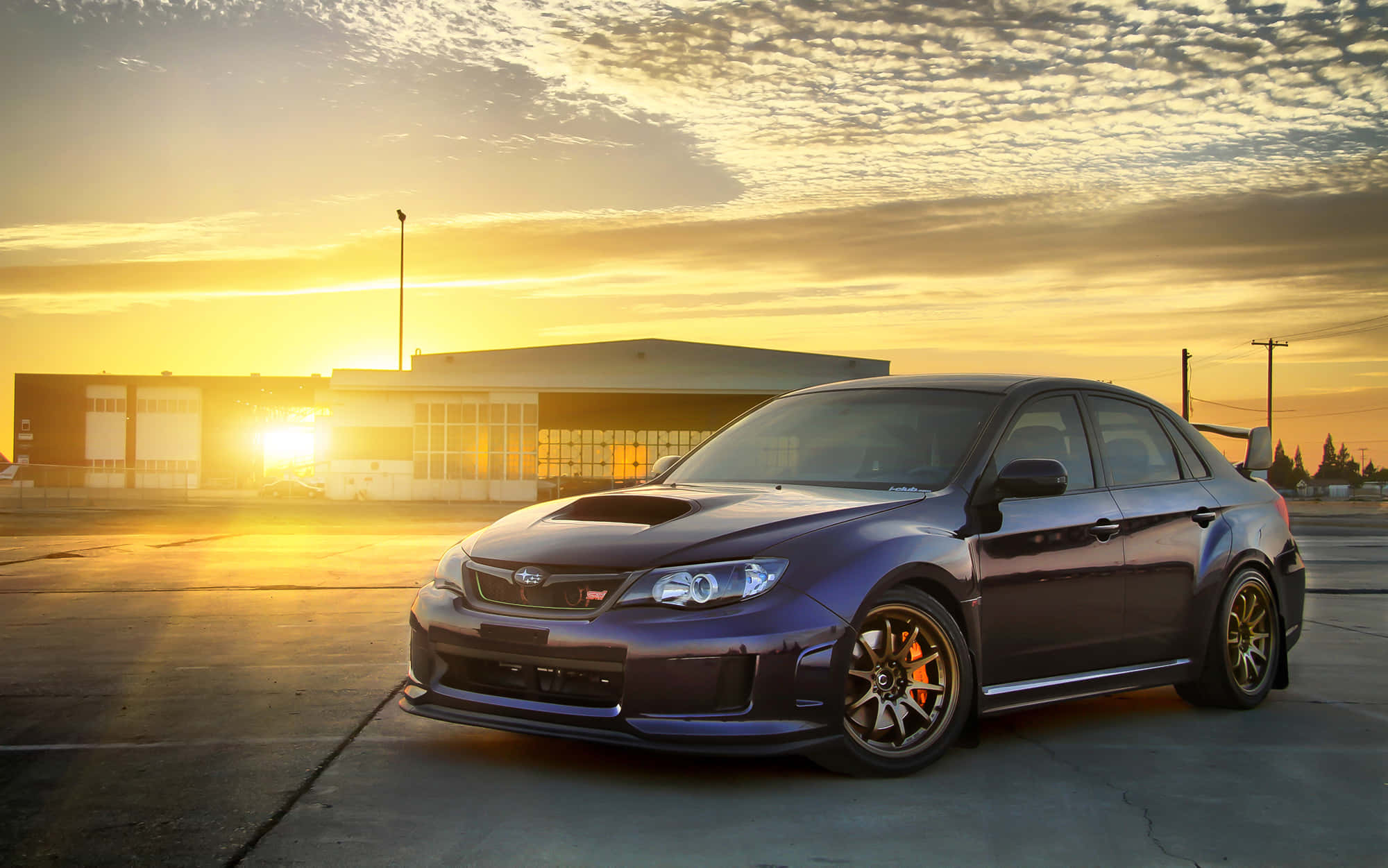 Subaru Impreza 桌布 壁紙 — 一架深紫色 Subaru WRX STI 停泊在混凝土上，金色夕陽光芒灑滿場景。