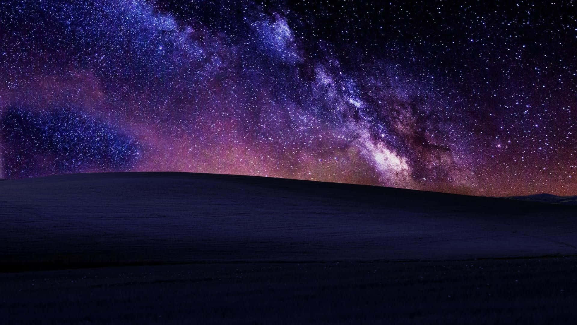  壁紙 — 一個黑暗起伏的山丘，在充滿活力的紫色和粉紅色星空下，襯托著發光的銀河。