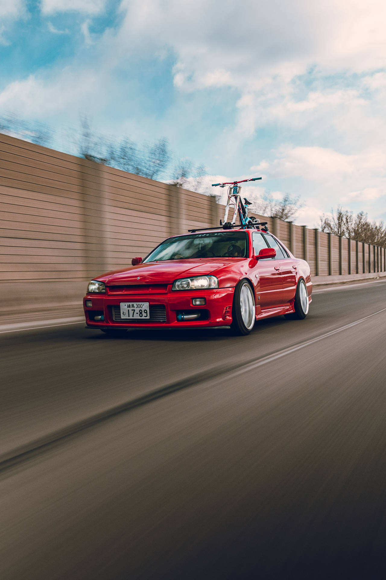 日產Skyline GTR R34在路面上駛過，背景為多雲天空