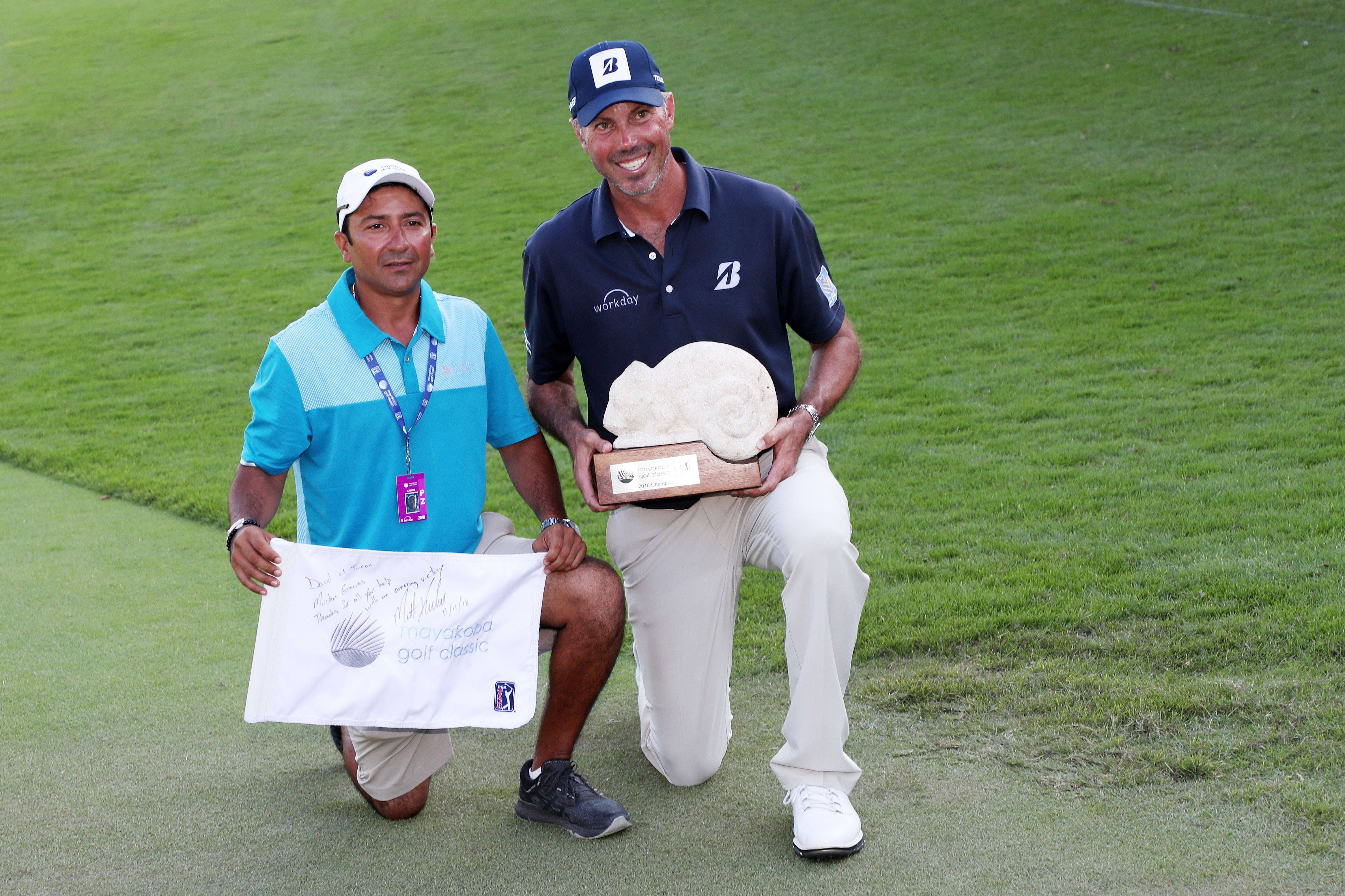 墨西哥球僮David Ortiz與美國高爾夫球手Matt Kuchar 壁紙 — 兩位微笑的高爾夫球手跪在茂密的綠色球道上，一人手持一個大貝殼形狀的獎盃，另一人手持一張簽名橫幅。