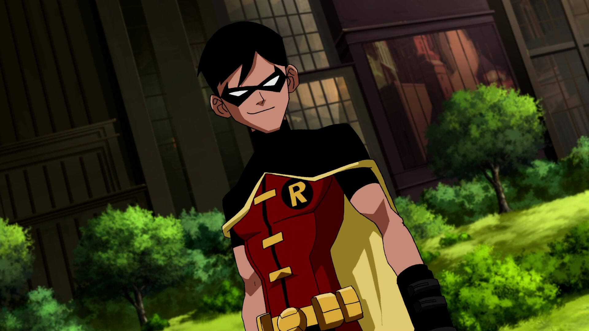 DC《少年正義》羅賓 壁紙 — 羅賓自信地站在一個綠意盎然的公園裡，身後有建築物，穿著他標誌性的紅黃黑服裝。