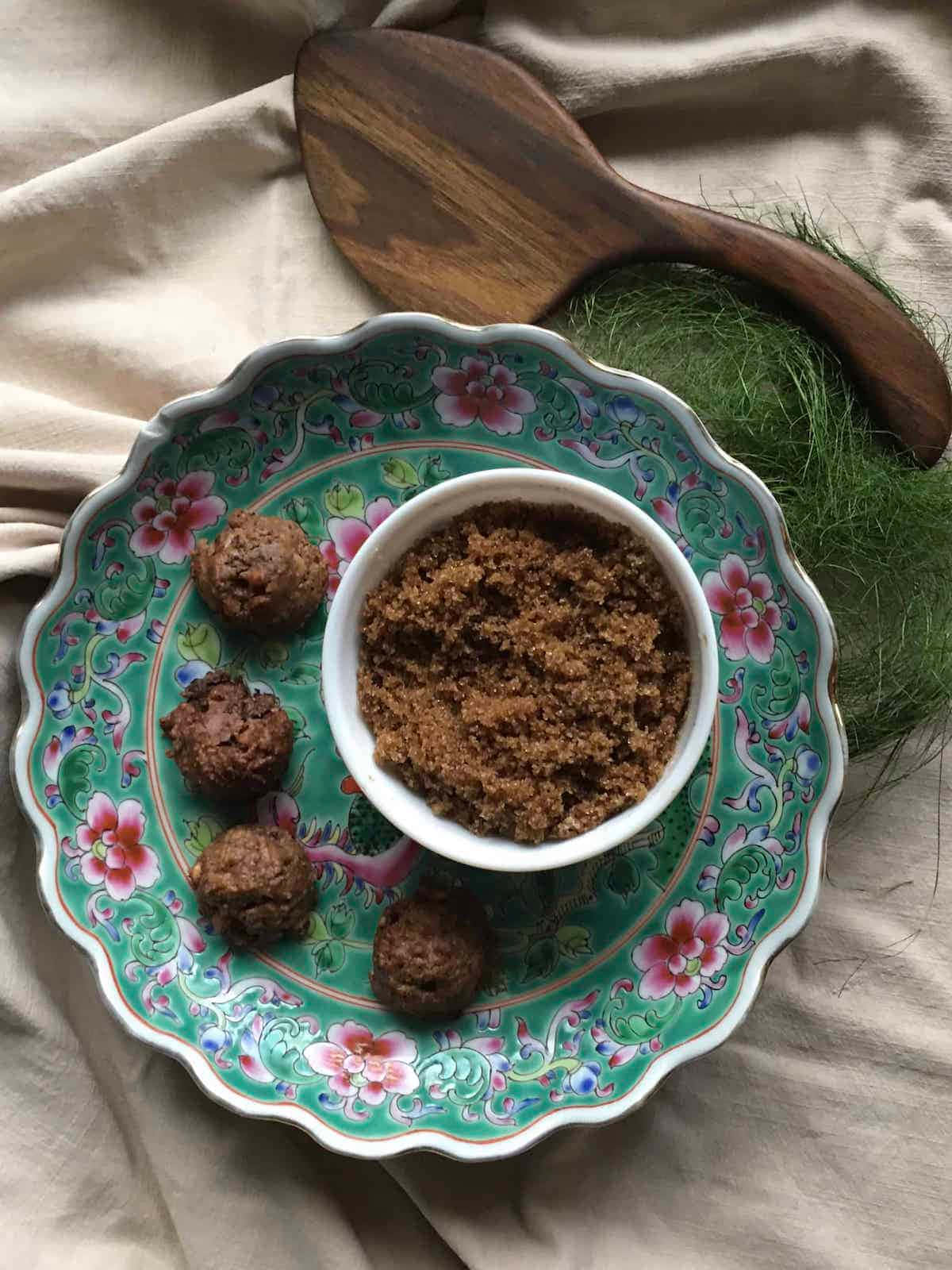  壁紙 — 一個裝飾性的綠色花卉碟上放著棕色肉丸和一碗紅糖，旁邊有新鮮蒔蘿和木勺，放在米色布上。