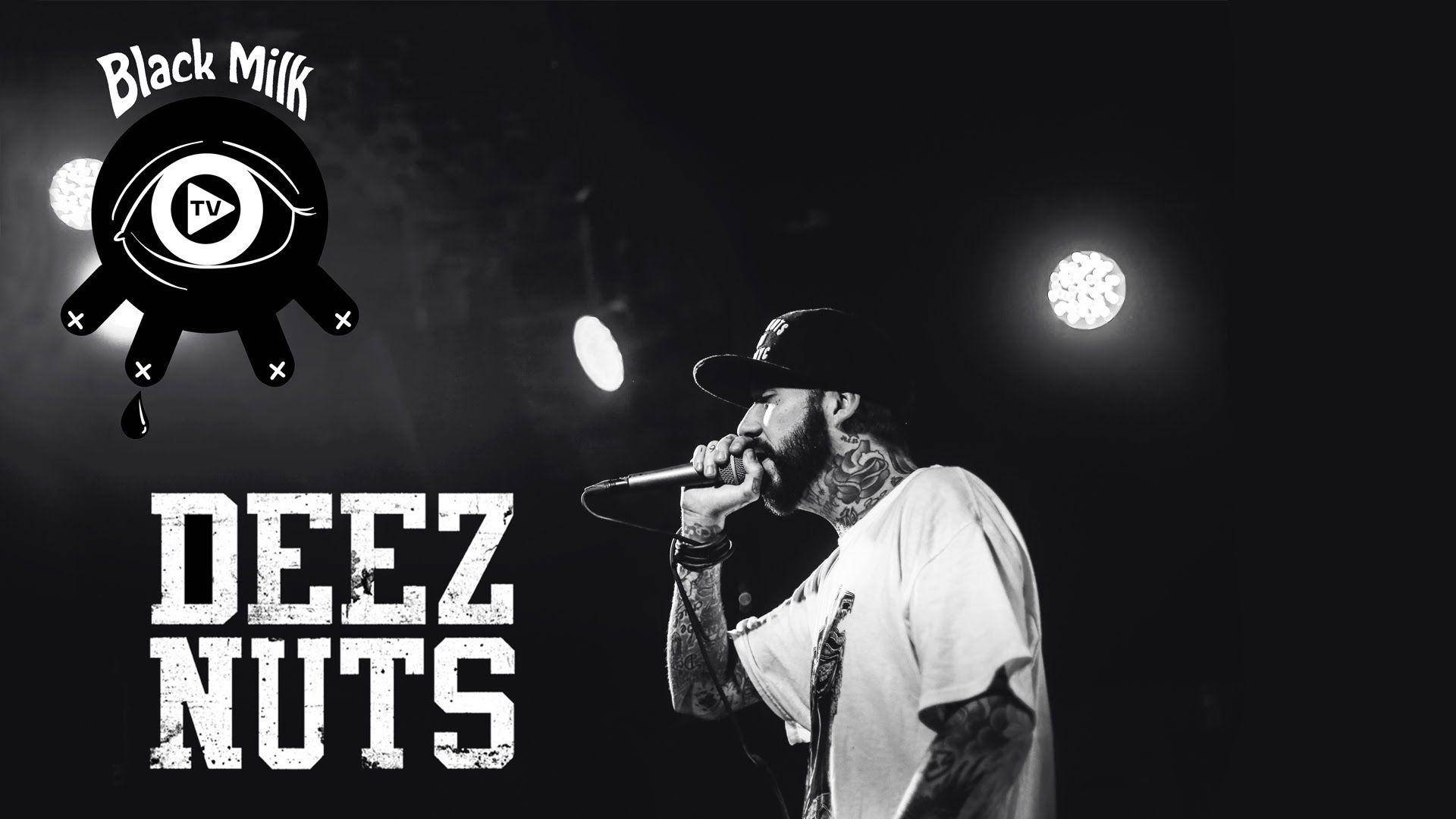 Deez Nuts 主唱 JJ Peters 壁紙 — 一位有紋身的說唱歌手在明亮的聚光燈下表演，帶有粗體白色字母的「Black Milk」和「DEEZ NUTS」文字。