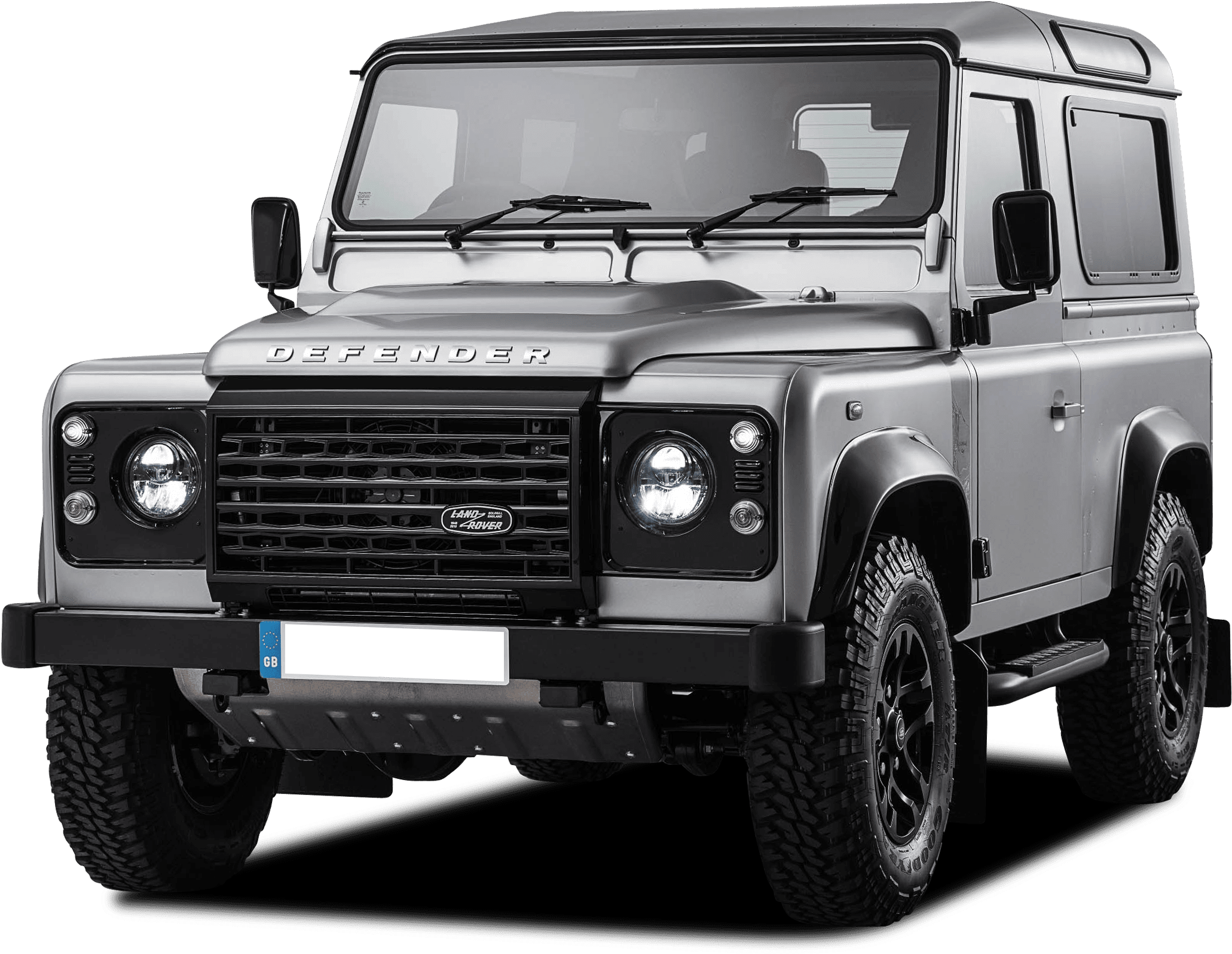 經典款路虎Defender 壁紙 — 一輛時尚的銀色 Land Rover Defender 在黑色背景下展現其堅固的設計和醒目的車頭燈。