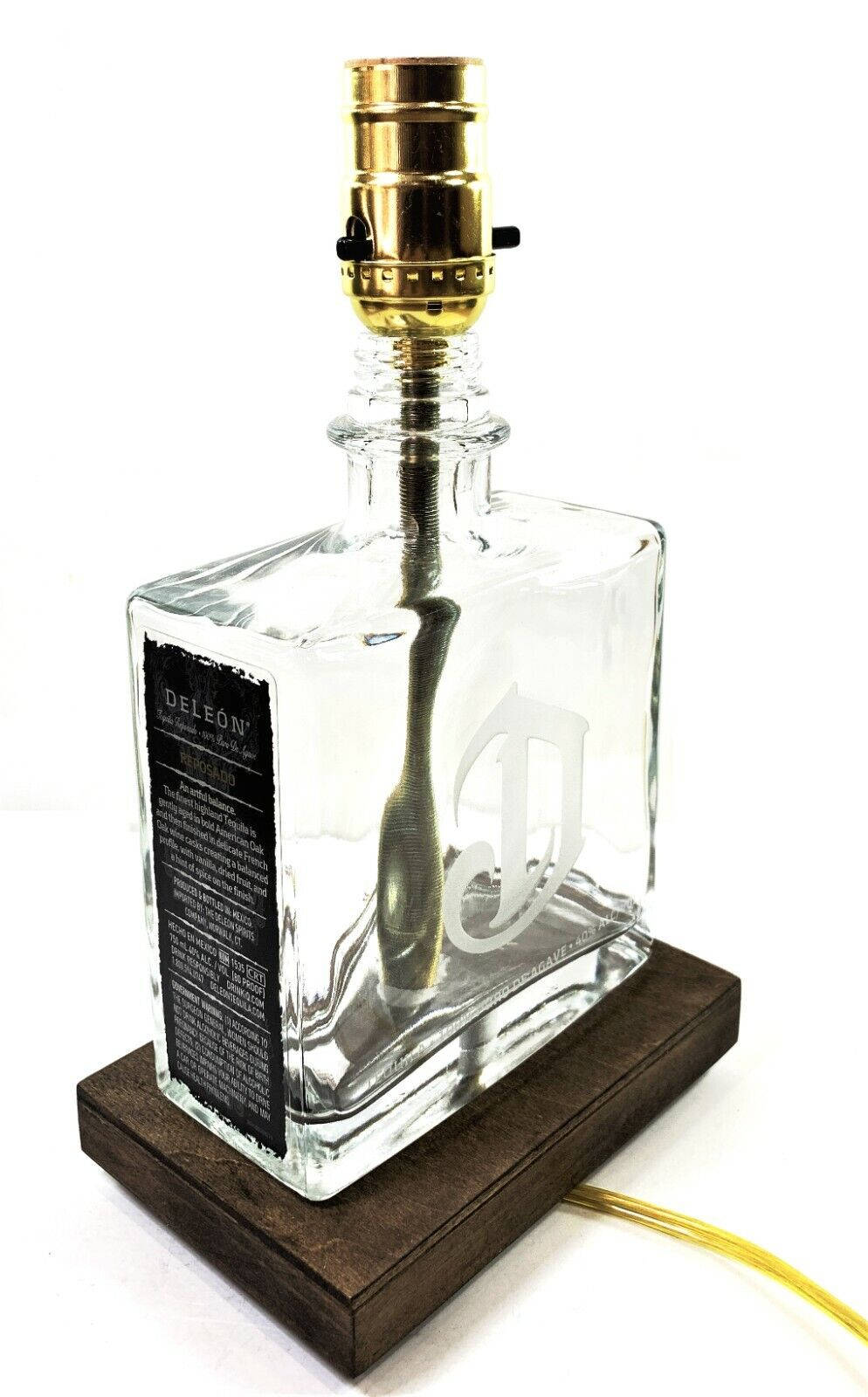 一個龍舌蘭酒瓶被改造成燈具，配有木質底座和金色燈座。