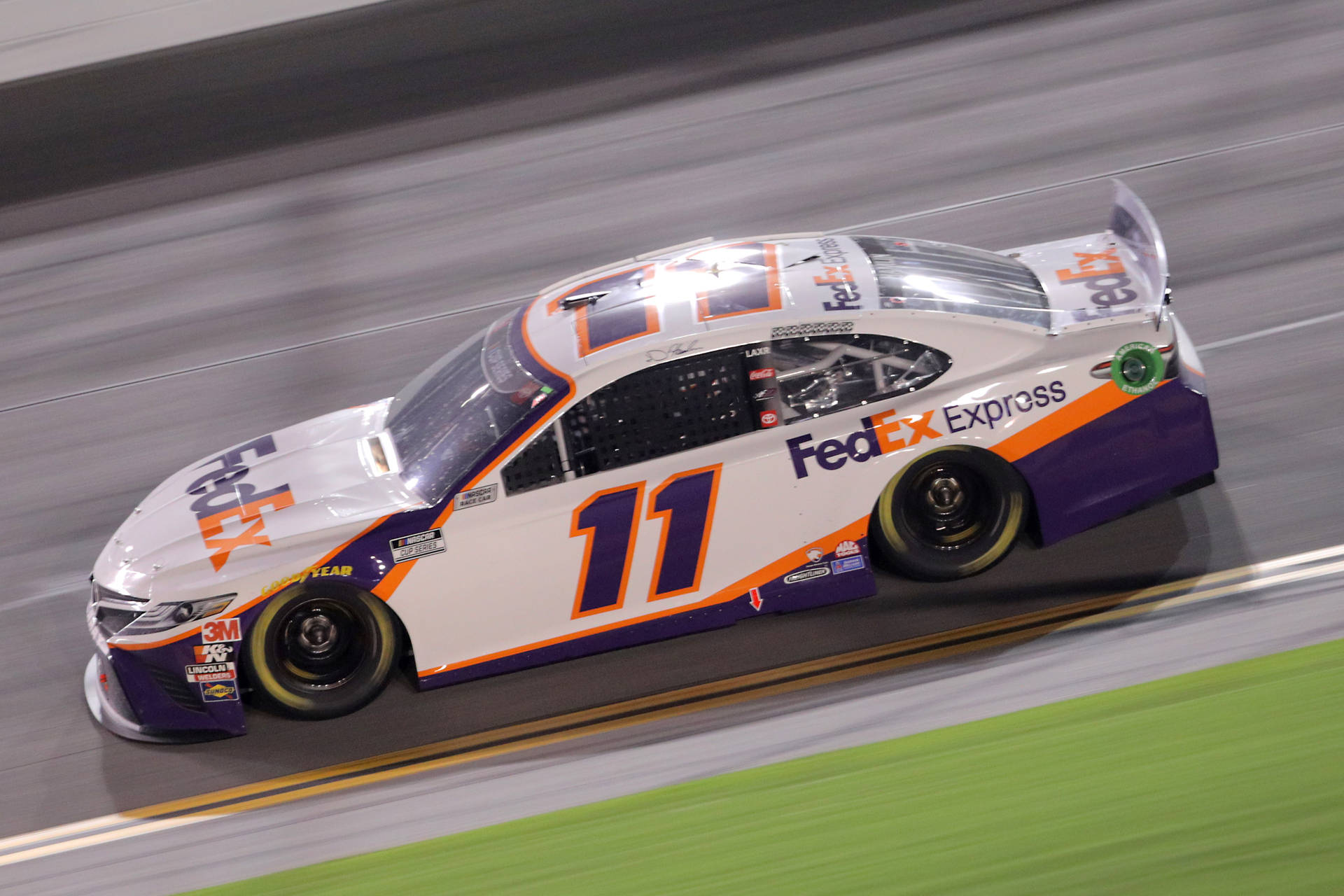 FedEx Express NASCAR 賽車在夜間賽道上高速行駛