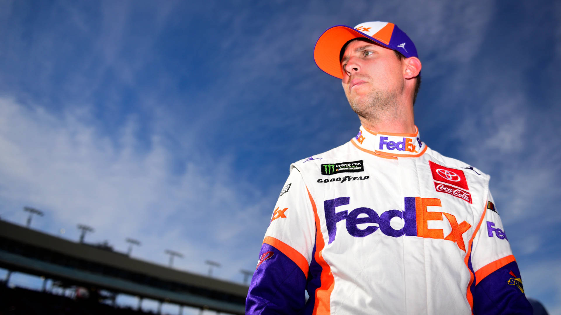 身穿FedEx賽車服的NASCAR車手站在戶外藍天下