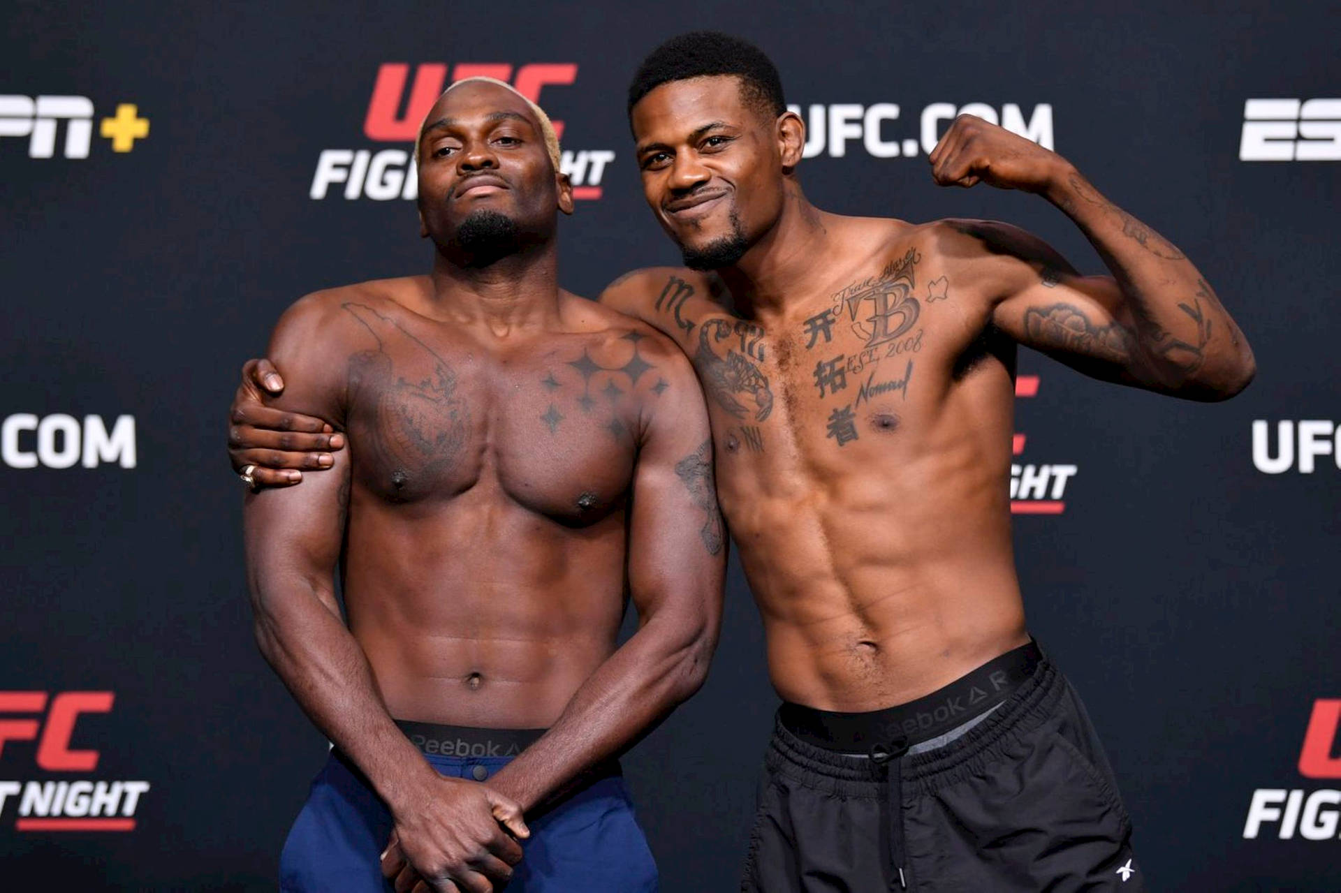 兩名赤膊的男性UFC拳手在稱重活動中擺姿勢。