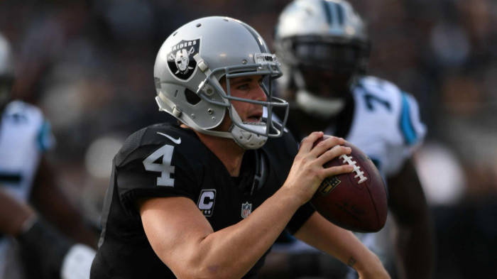 身穿黑色球衣的NFL四分衛在日間比賽中準備投擲橄欖球。