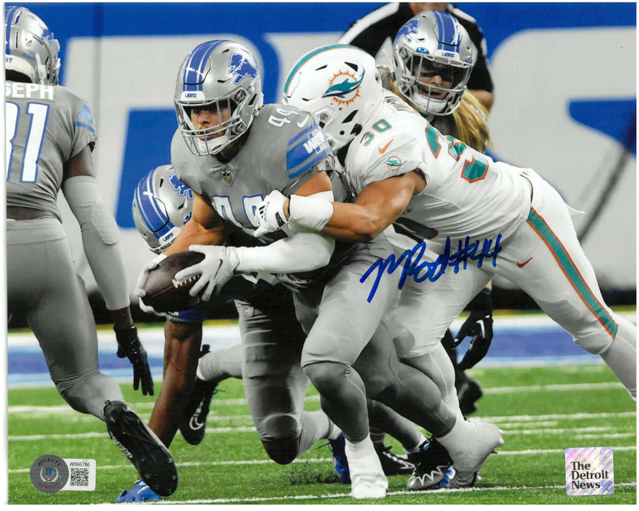  壁紙 — 底特律雄獅隊的跑衛在激烈的NFL比賽中，於充滿活力的綠色球場上被邁阿密海豚隊的防守球員擒抱。