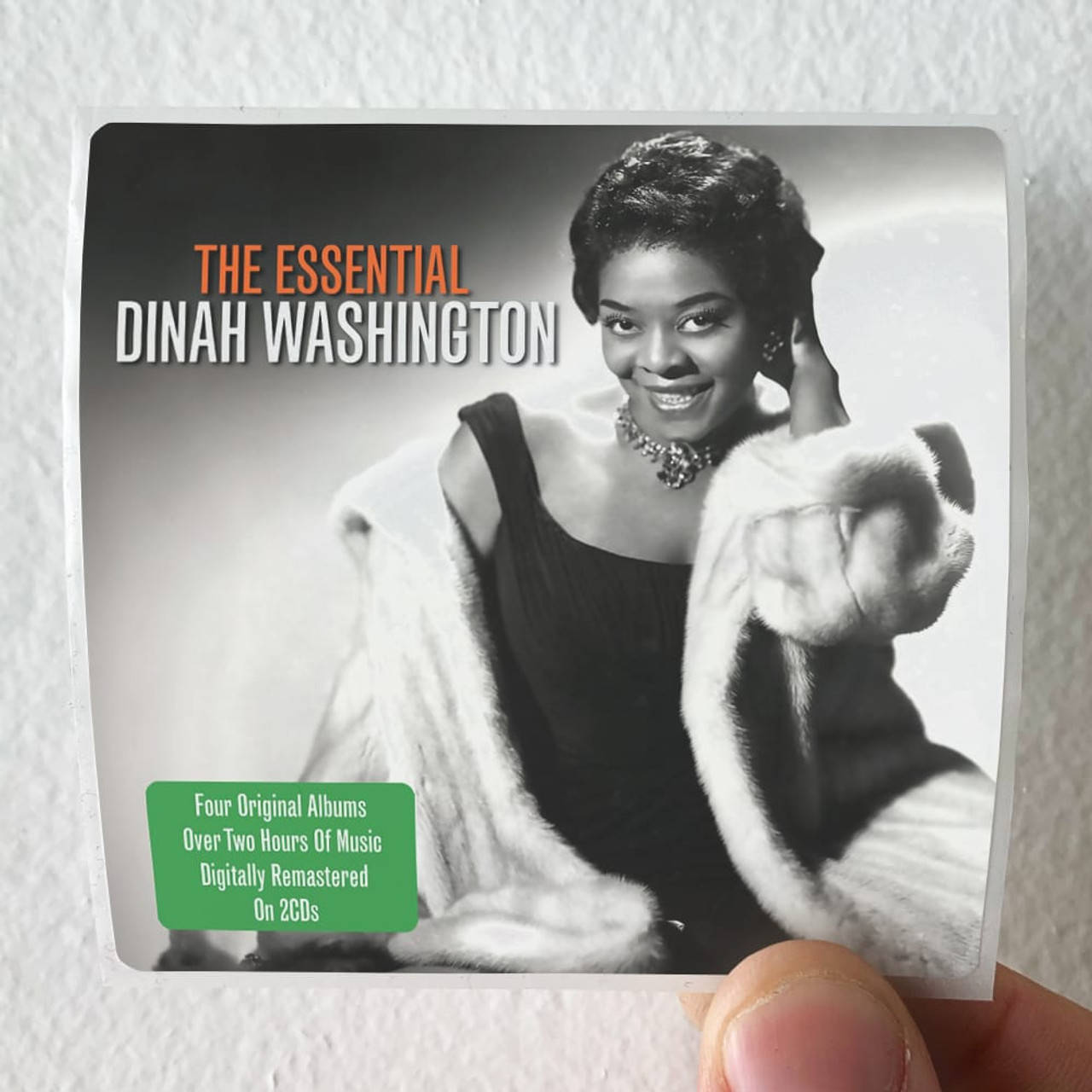 Dinah Washington 精選輯 壁紙 — 一隻手拿著一張Dinah Washington的復古專輯封面，她穿著黑色連衣裙和白色毛皮披肩，在攝影棚背景下溫暖地微笑。