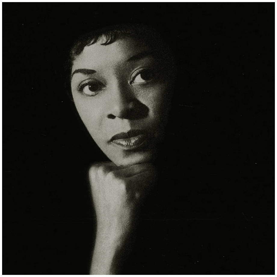 Dinah Washington 歌手音樂家 壁紙 — 一個引人注目的黑白肖像，一位女士在黑暗背景下托腮沉思。