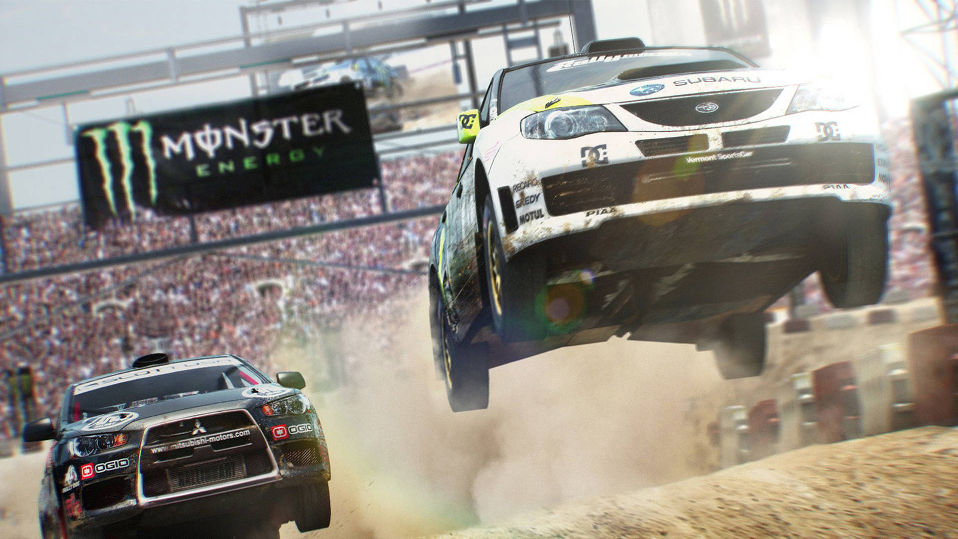 Dirt 3 速霸陸對戰三菱 壁紙 — 一輛白色拉力賽車在泥土上空飛翔，而一輛黑色賽車在Monster Energy橫幅下在下方奔馳。