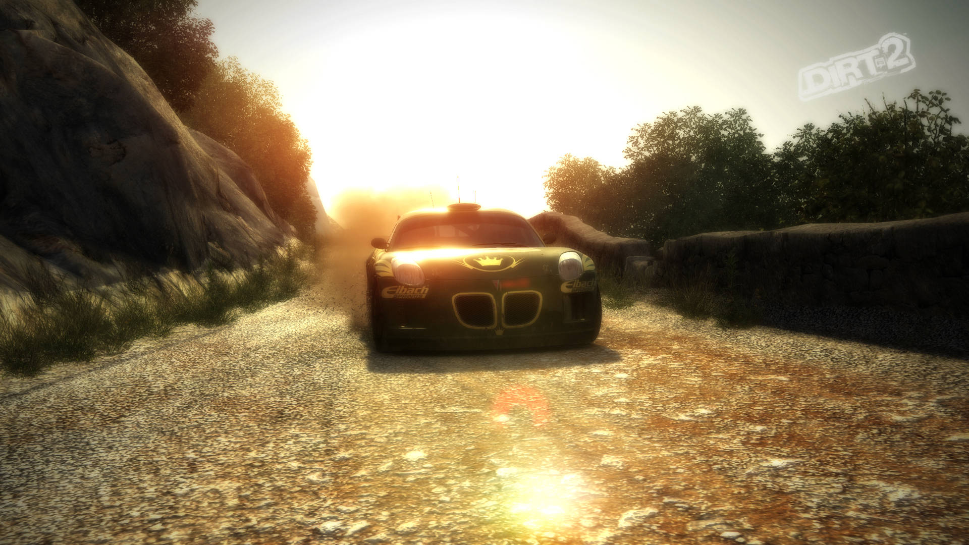 《Dirt Rally》中Pontiac Solstice的激烈賽道競速 壁紙 — 一輛拉力賽車在陽光明媚的碎石路上飛馳，兩旁是岩石峭壁和樹木。