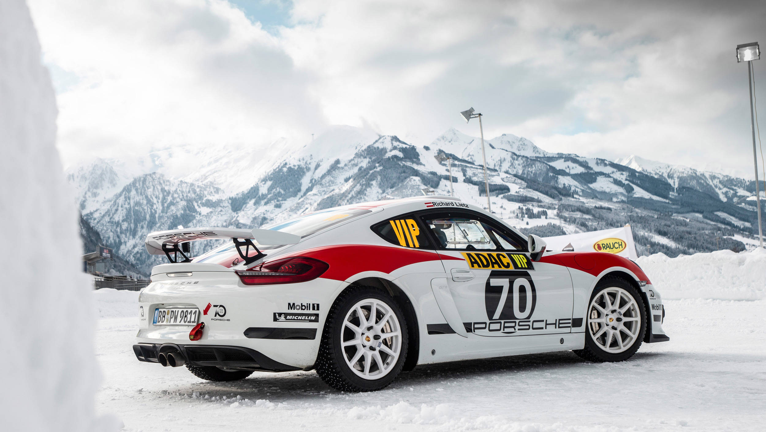 《Dirt Rally》遊戲中的Porsche Cayman 壁紙 — 一輛帶有紅色點綴和70號的白色保時捷911賽車停泊在雪地上，背景是白雪覆蓋的山脈。