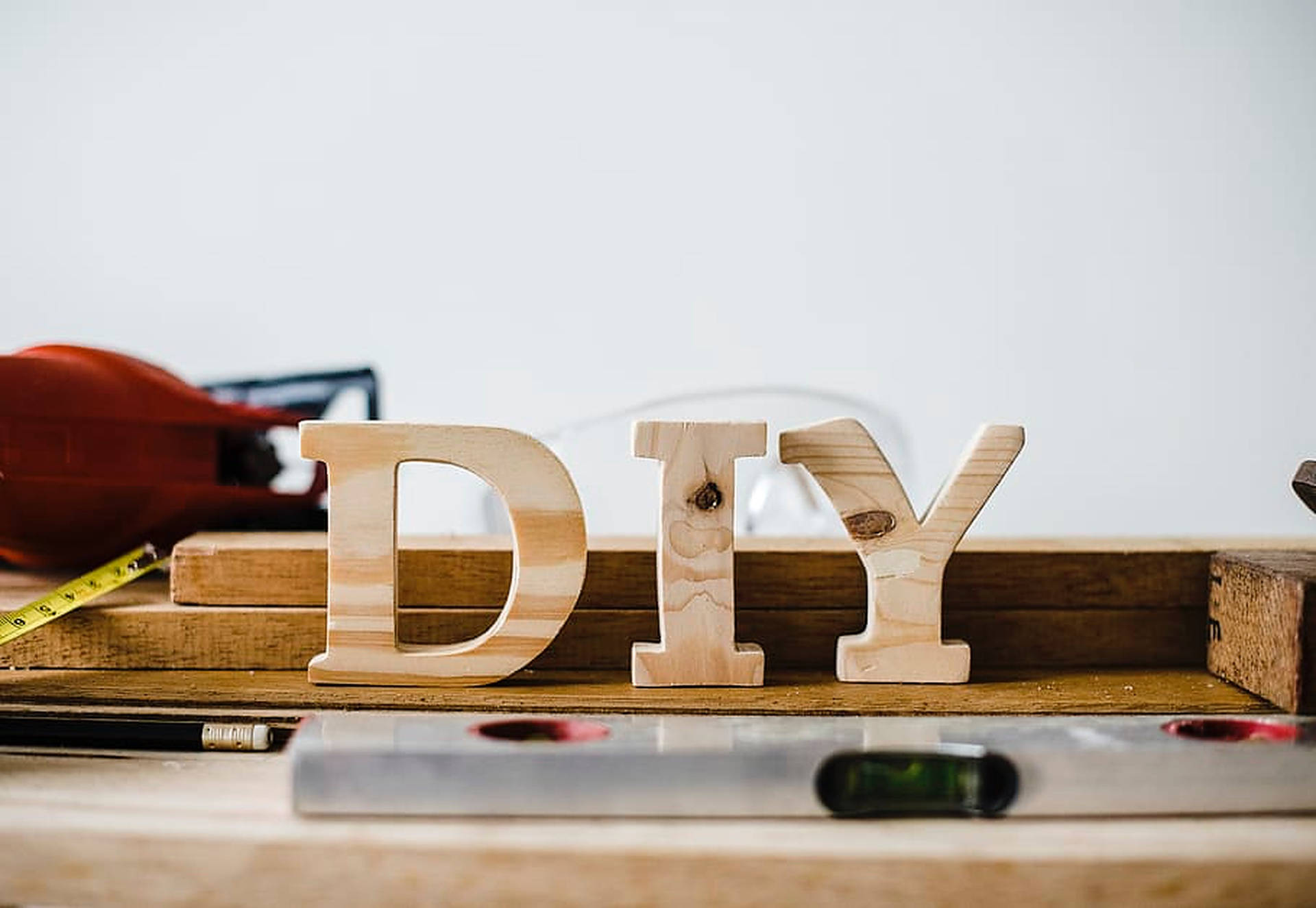 DIY字母Y 壁紙 — 木製DIY字母放在工作台上，周圍有水平尺、捲尺和電鑽等工具。