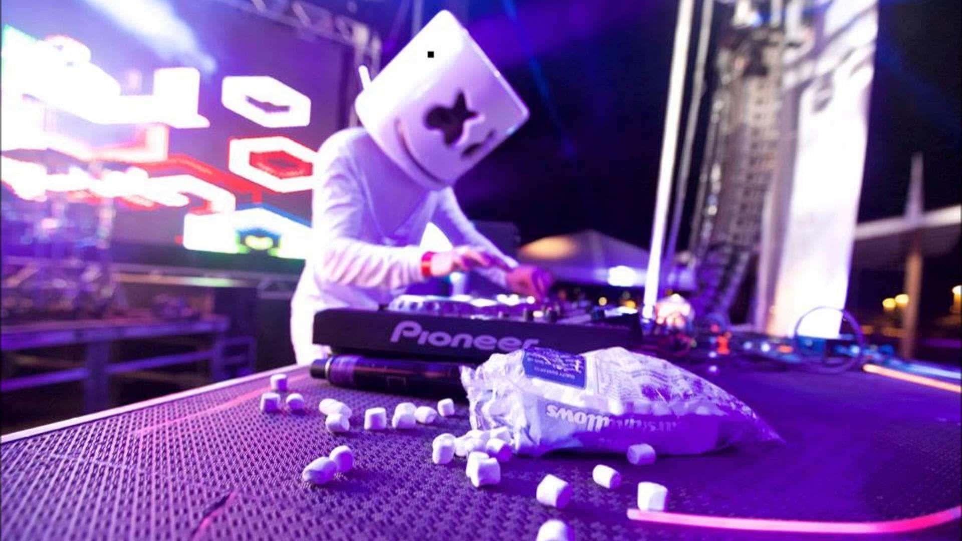 Marshmello 桌布 壁紙 — DJ Marshmello 在夜晚的霓虹燈下表演，桌上散落著棉花糖。