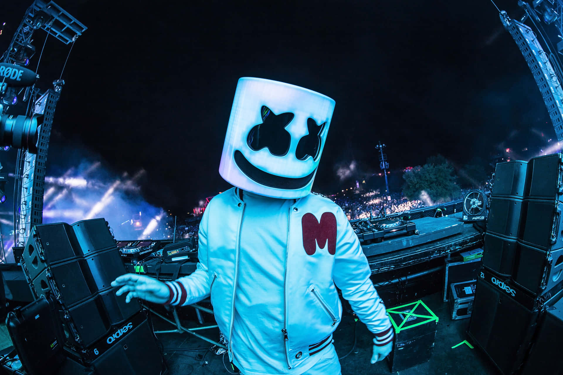 DJ Marshmello 戴著白色頭盔和外套，在夜晚的燈光舞台上。