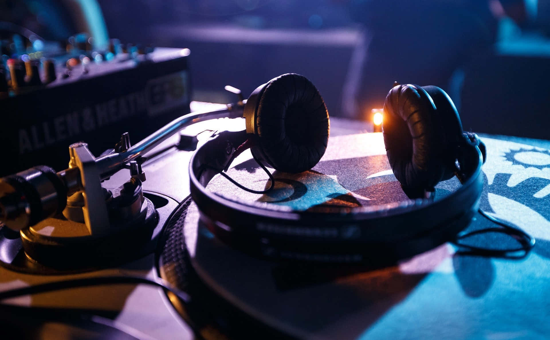 DJ 桌布 壁紙 — DJ耳機特寫，放在唱盤上，在藍色和橙色的舞台燈光下。