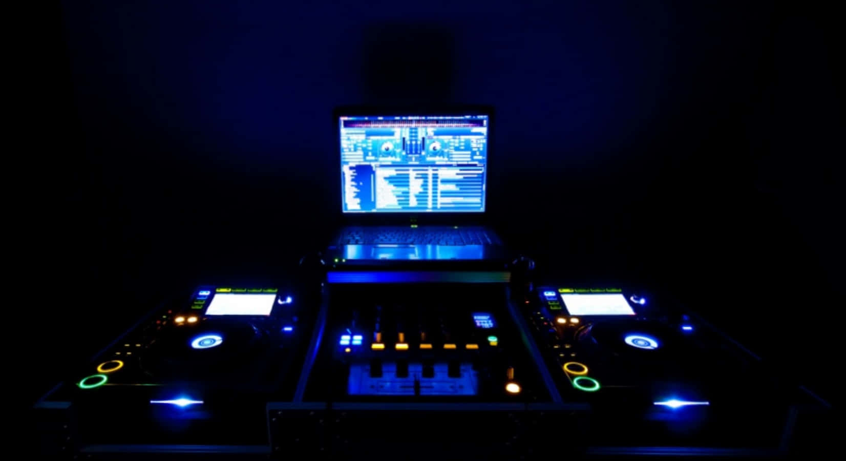 DJ音樂控制台圖 壁紙 — DJ 設備在黑暗的房間中發出藍色和橙色的光芒，手提電腦顯示音樂軟件。