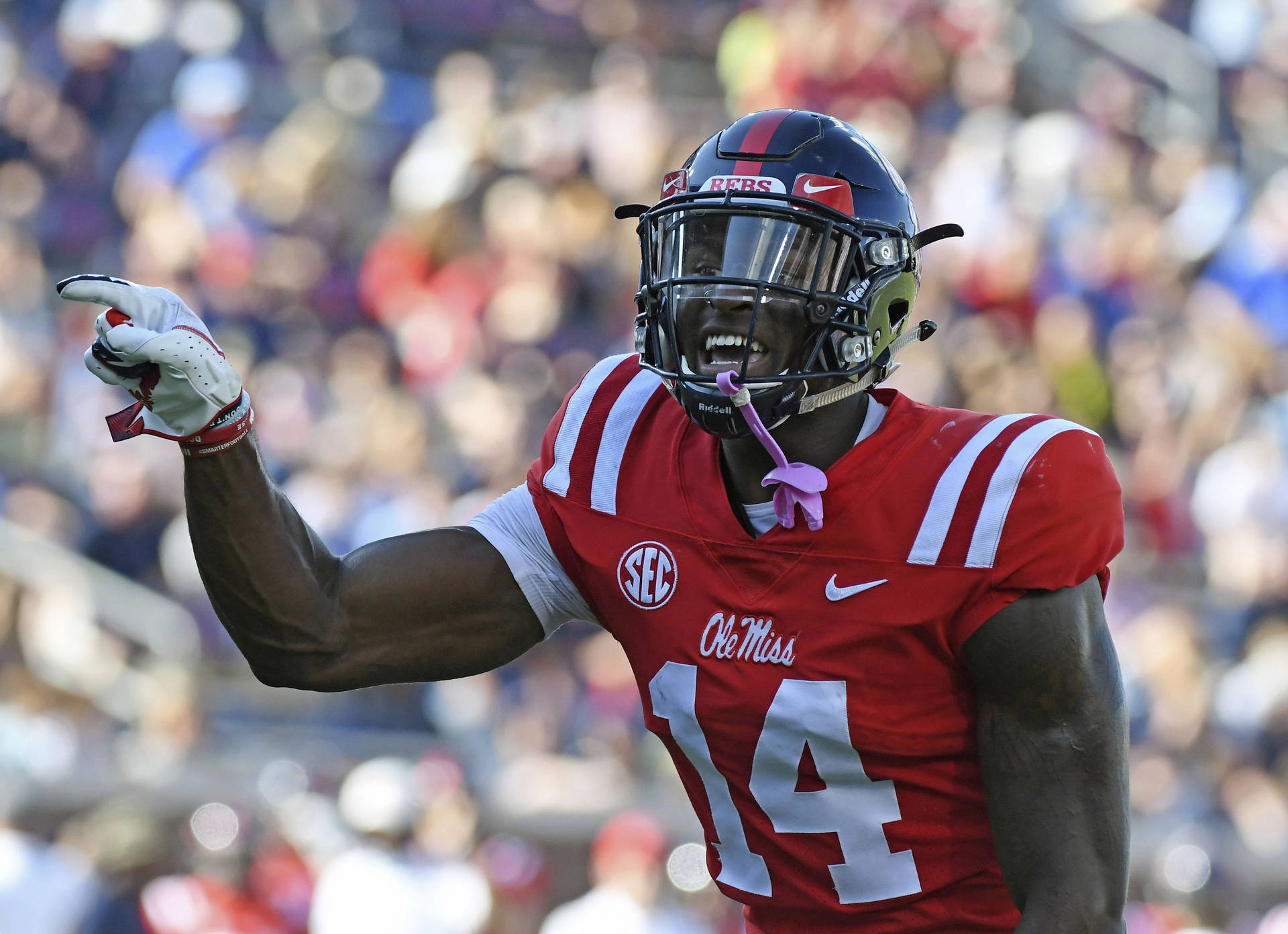穿著紅色 Ole Miss 14號球衣的美式足球員在比賽中舉起拳頭慶祝。