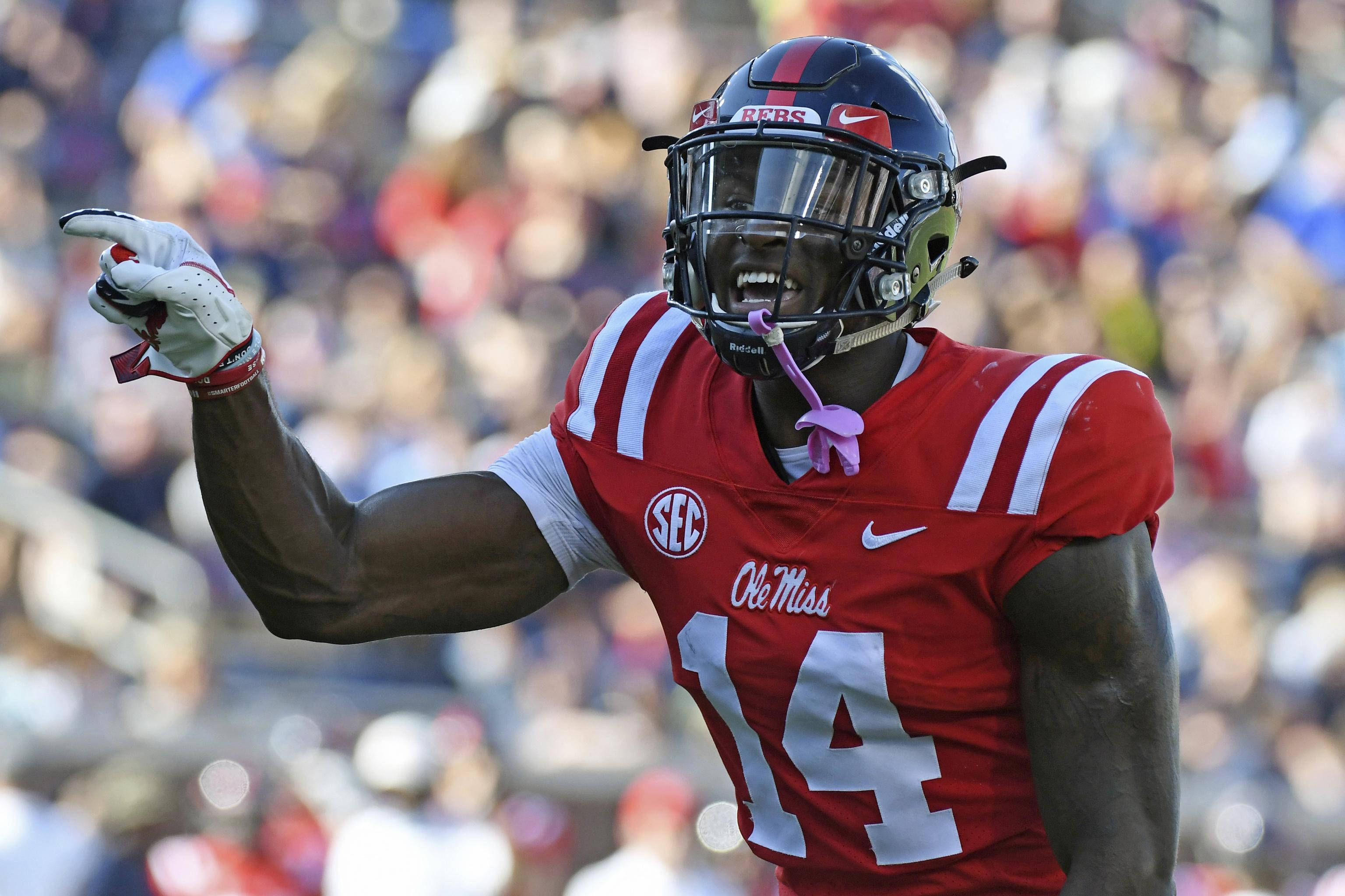 DK麥特卡夫 指著某物 壁紙 — 一名身穿紅色 Ole Miss 14 號球衣的足球運動員在比賽中舉起拳頭慶祝。
